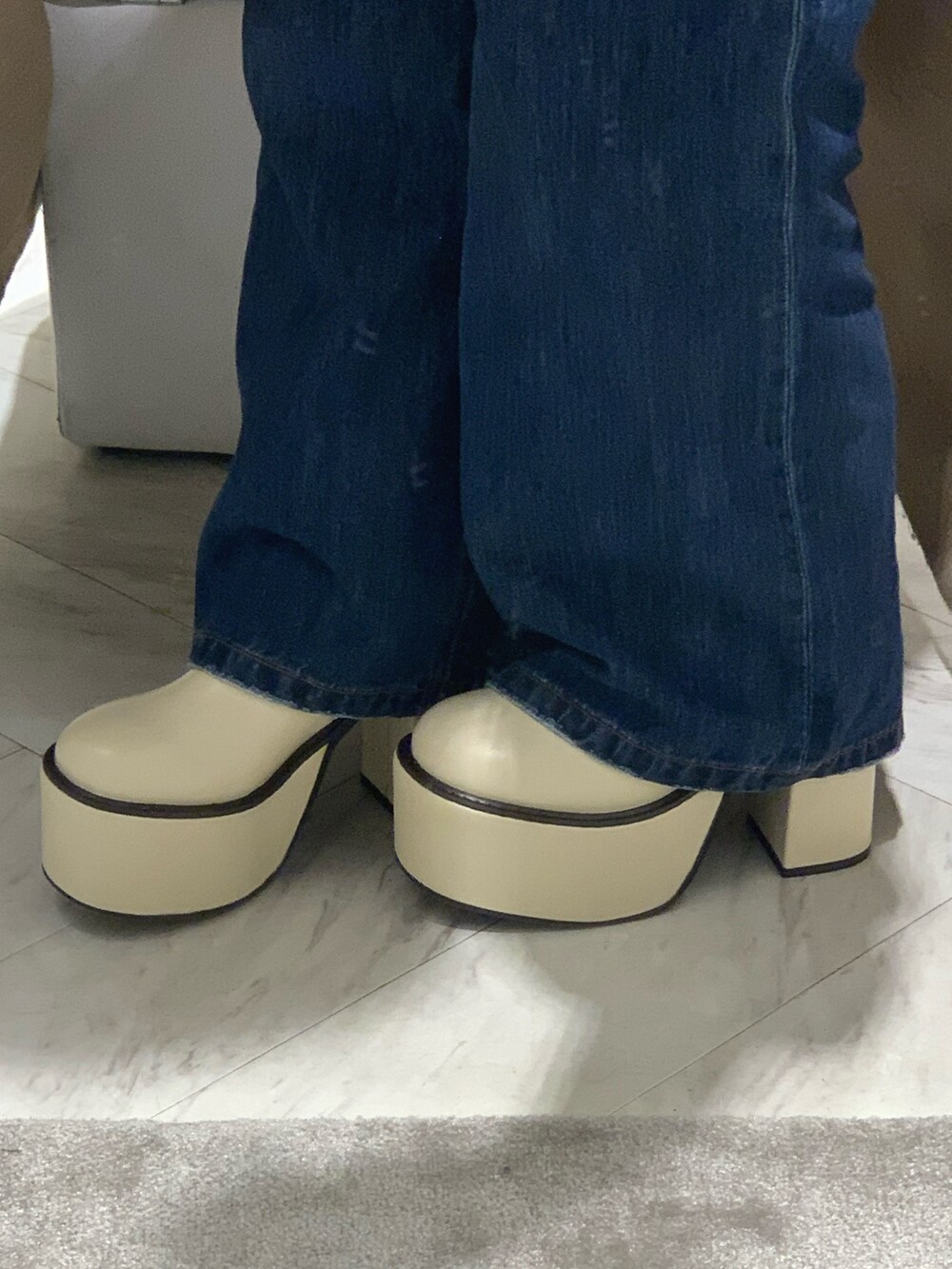 ブルー系のデニムパンツ、ホワイト系のカーディガン/ボレロ、ホワイト系のブーツを着用したレディースの冬コーディネートの7枚目の写真