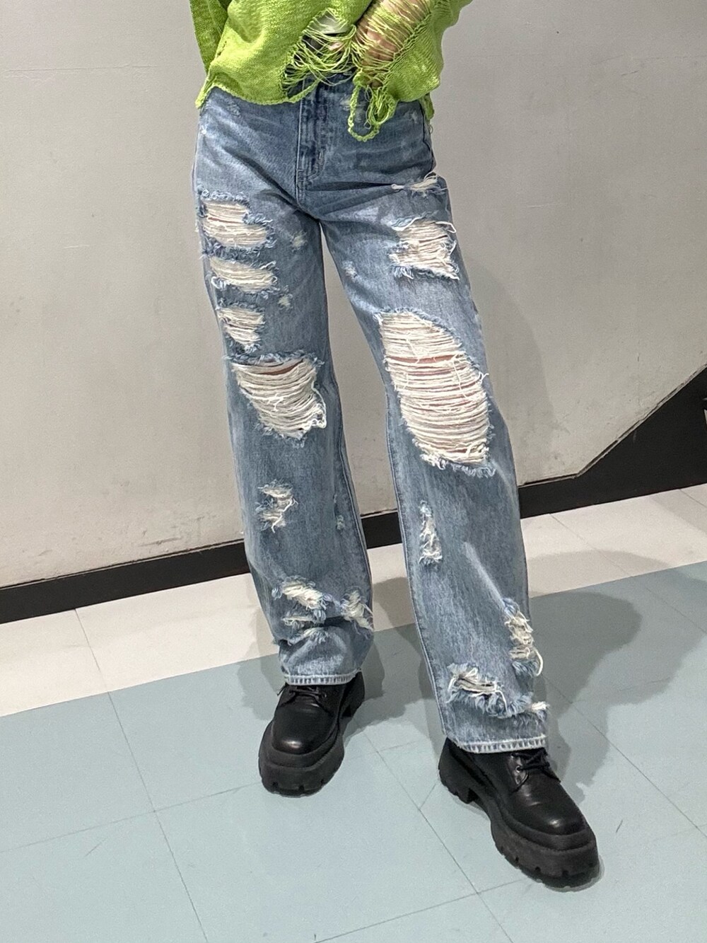 グリーン系のニット/セーター、ブルー系のデニムパンツ、ブラック系のブーツを着用したレディースの春コーディネートの4枚目の写真