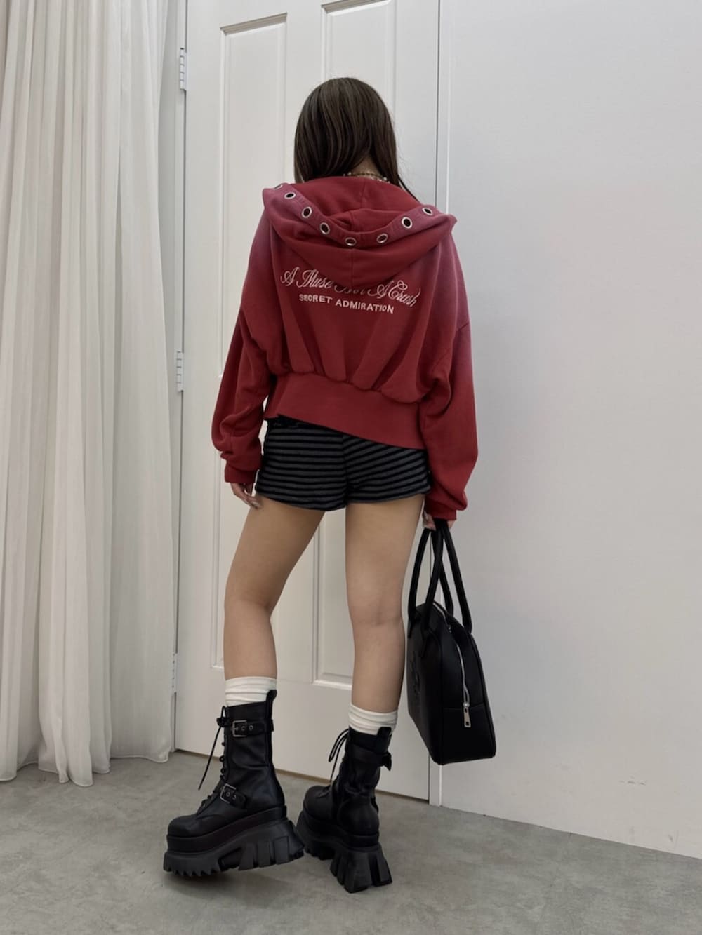ブラック系のボストンバッグ、レッド系のパーカー、ブラック系のブーツを着用したレディースの夏コーディネートの3枚目の写真
