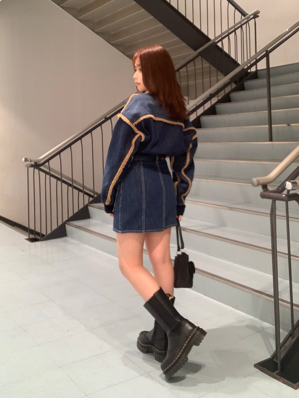 ブルー系のブルゾン、ブルー系のデニムスカート、ブラック系のブーツを着用したレディースの秋コーディネートの2枚目の写真