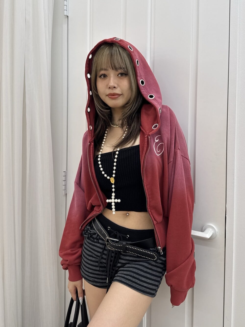 ブラック系のボストンバッグ、レッド系のパーカー、ブラック系のブーツを着用したレディースの夏コーディネートの4枚目の写真