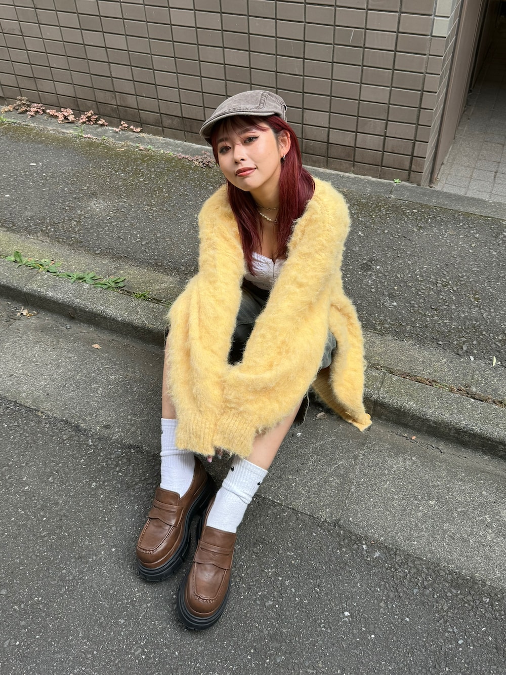 イエロー系のニット/セーター、ブラウン系のローファーを着用したレディースの夏コーディネートの2枚目の写真