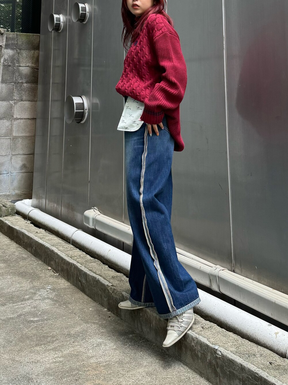 レッド系のニット/セーター、ブルー系のデニムパンツを着用したレディースの夏コーディネートの2枚目の写真