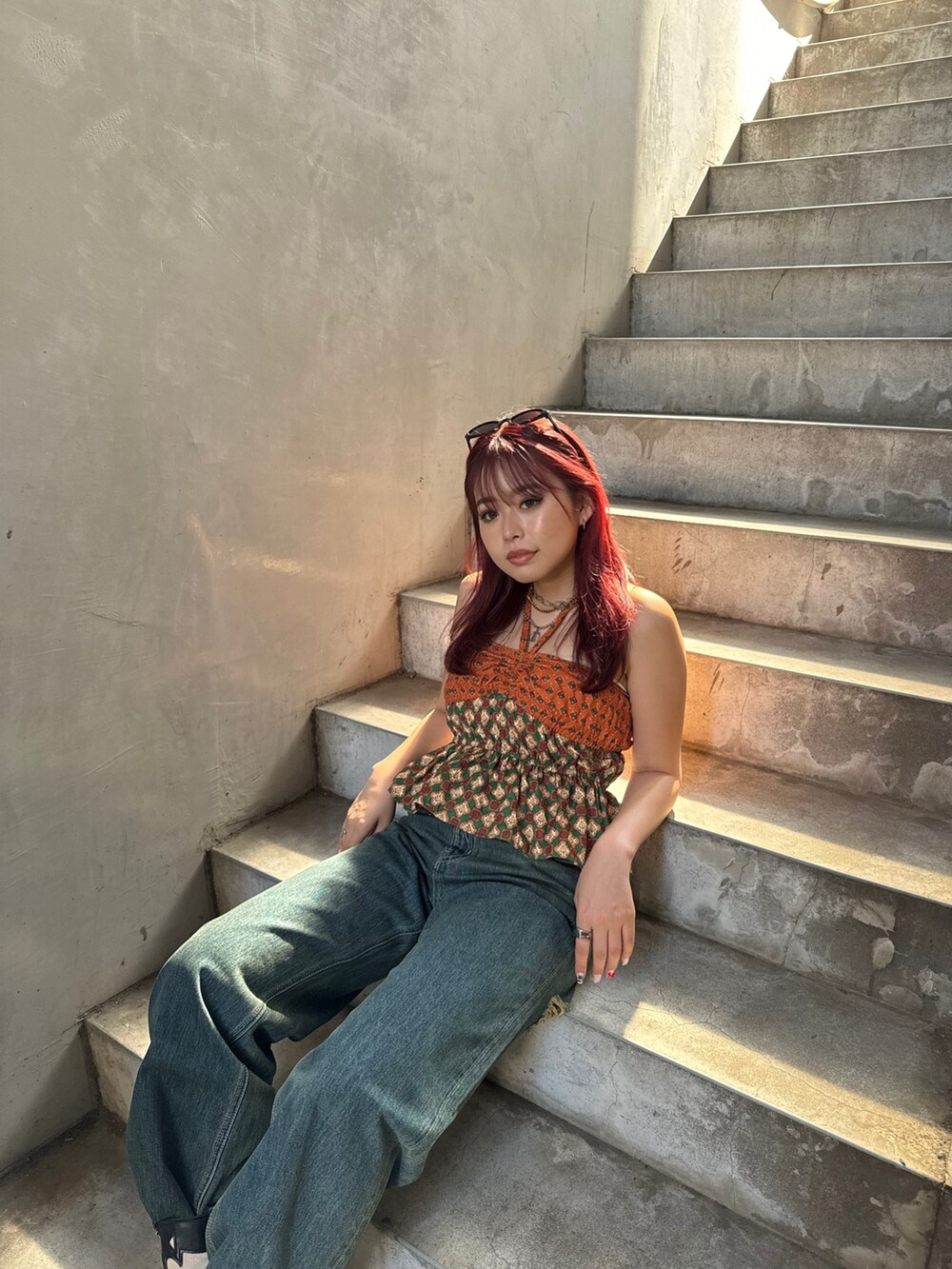 オレンジ系のキャミソール、ブルー系のデニムパンツを着用したレディースの夏コーディネートの4枚目の写真