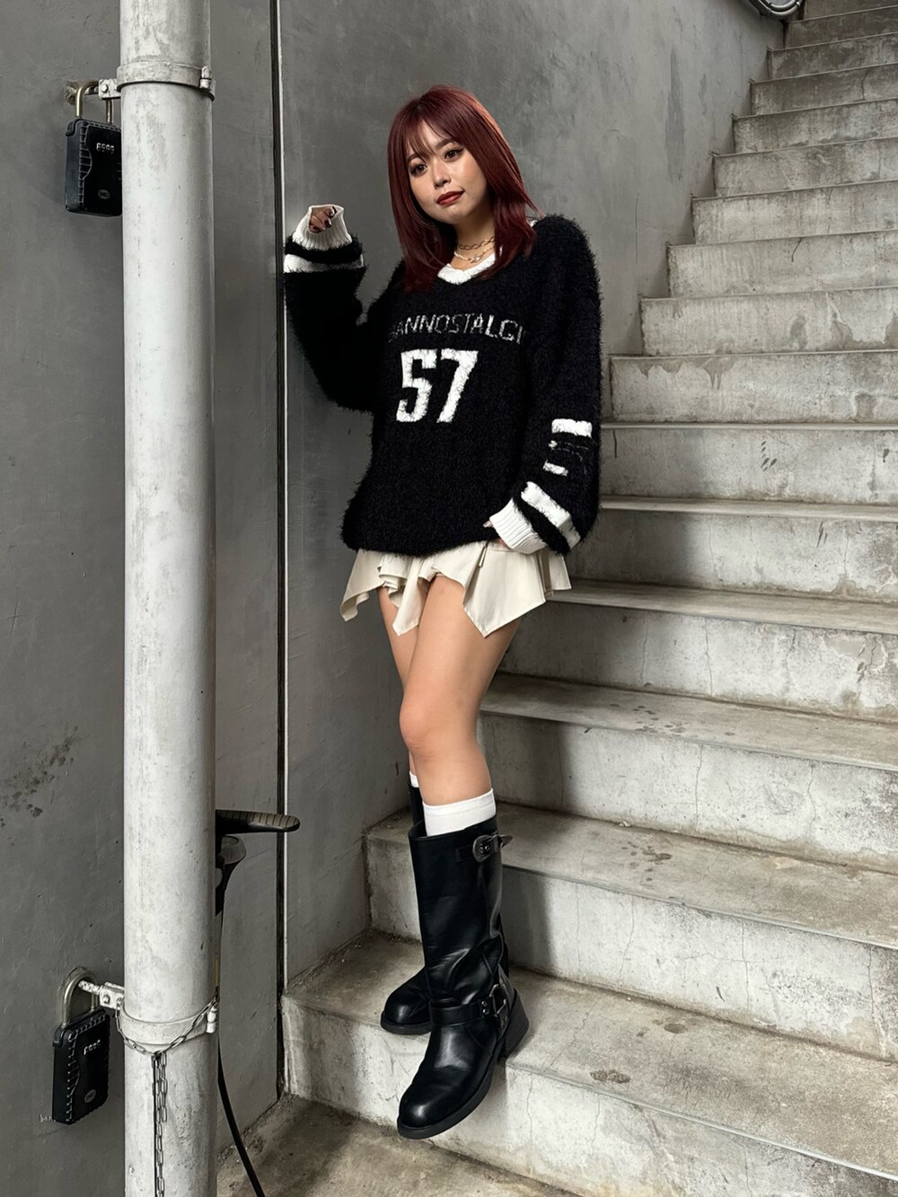 ブラック系のニット/セーター、ホワイト系のスカート、ブラック系のブーツを着用したレディースの秋コーディネートの2枚目の写真