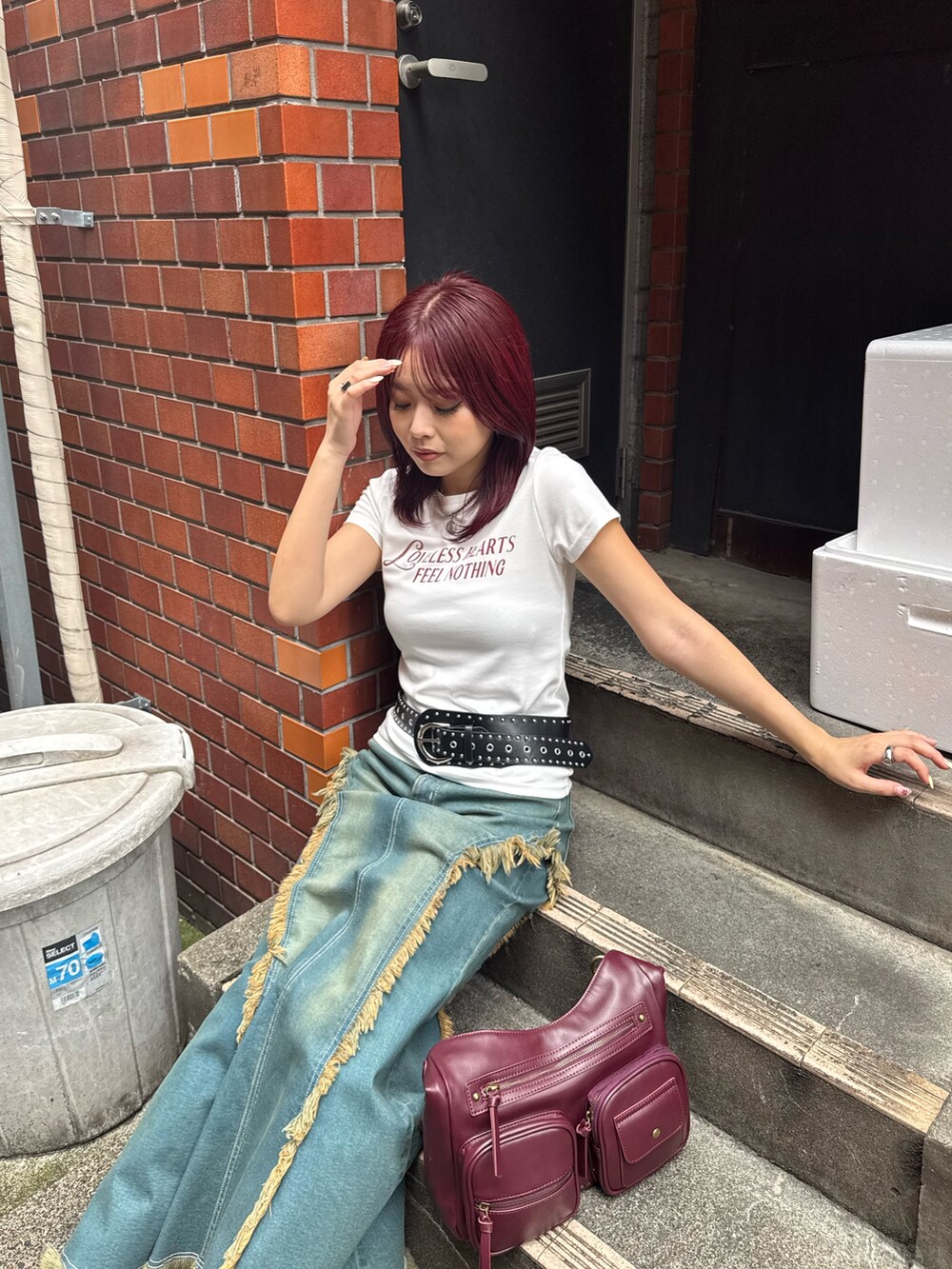 ブルー系のデニムスカート、ブラック系のブーツ、レッド系のハンドバッグを着用したレディースの夏コーディネートの4枚目の写真