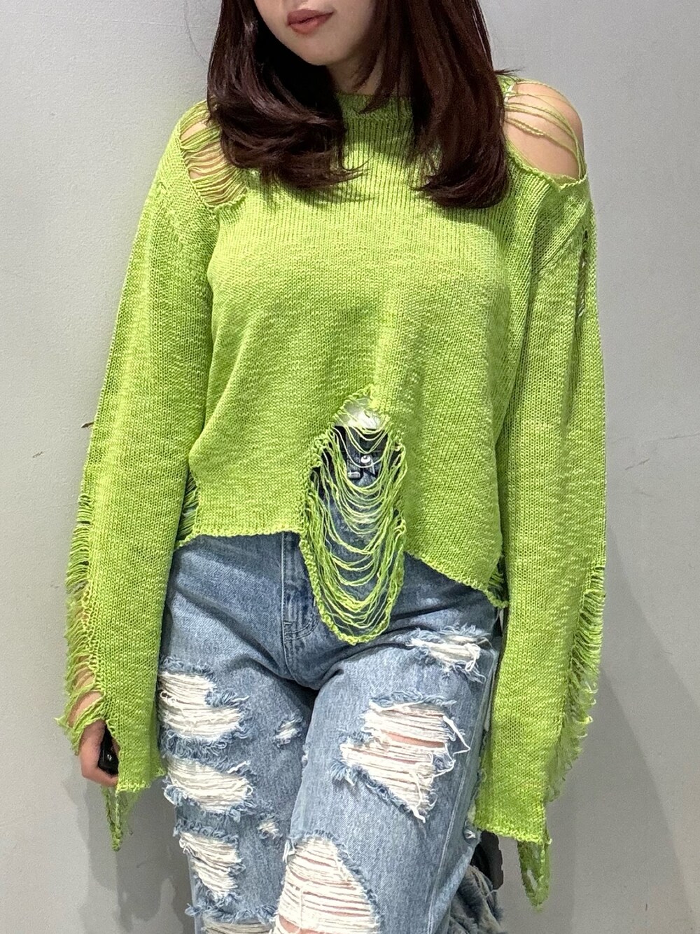 グリーン系のニット/セーター、ブルー系のデニムパンツ、ブラック系のブーツを着用したレディースの春コーディネートの2枚目の写真