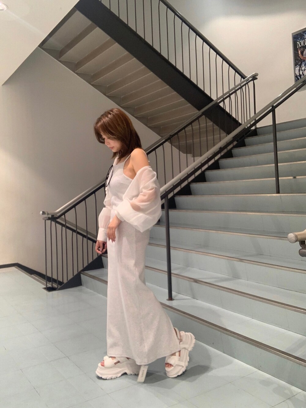 グレー系のワンピース、ホワイト系のシャツ/ブラウス、ホワイト系のサンダルを着用したレディースの春コーディネートの2枚目の写真