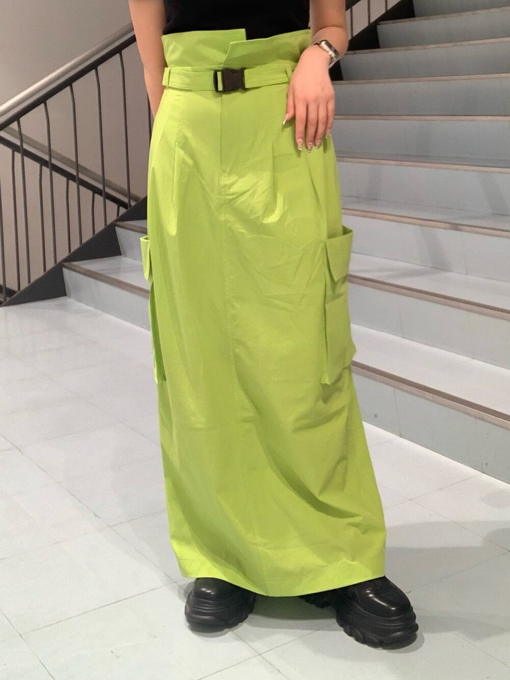 ブラック系のTシャツ/カットソー、グリーン系のスカート、ブラック系のスニーカーを着用したレディースの春コーディネートの5枚目の写真