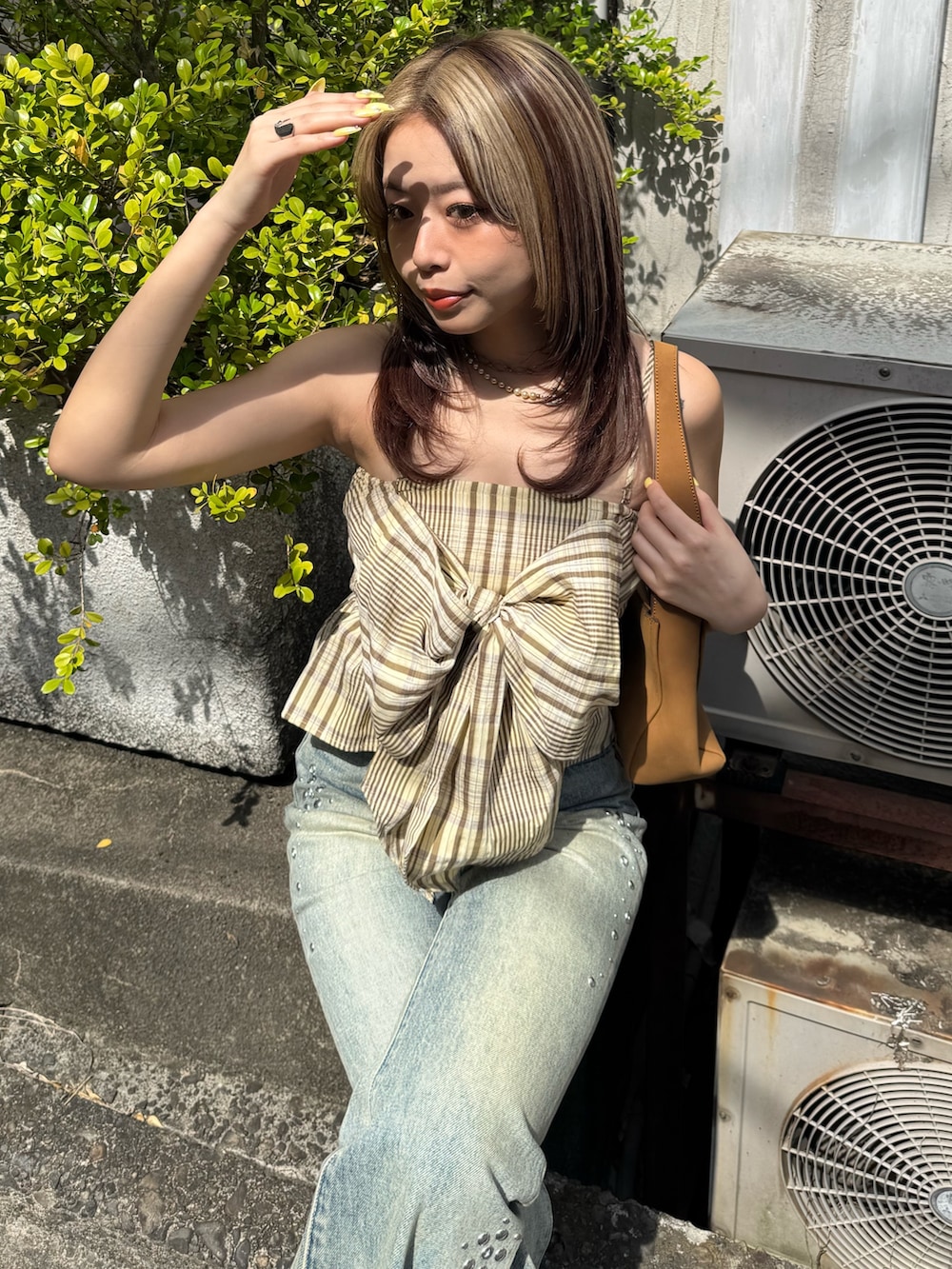 イエロー系のキャミソール、ブルー系のデニムパンツ、ブラウン系のハンドバッグを着用したレディースの春コーディネートの4枚目の写真