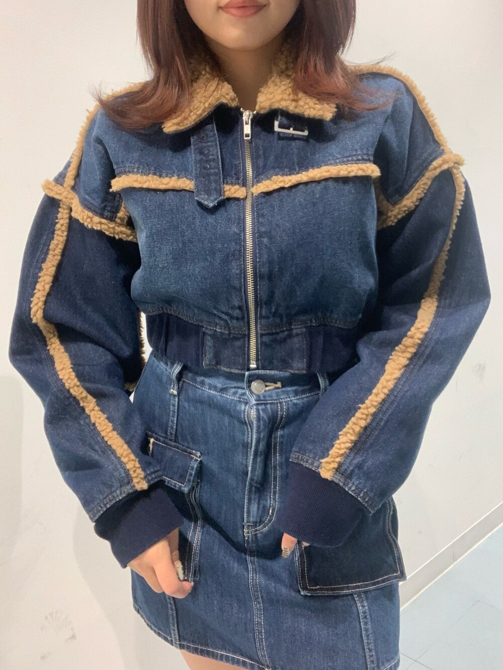 ブルー系のブルゾン、ブルー系のデニムスカート、ブラック系のブーツを着用したレディースの秋コーディネートの3枚目の写真