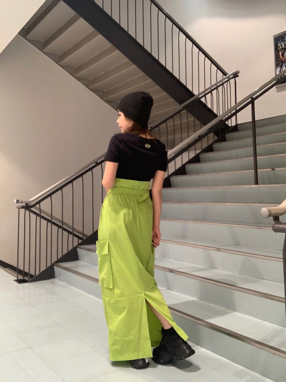 ブラック系のTシャツ/カットソー、グリーン系のスカート、ブラック系のスニーカーを着用したレディースの春コーディネートの2枚目の写真