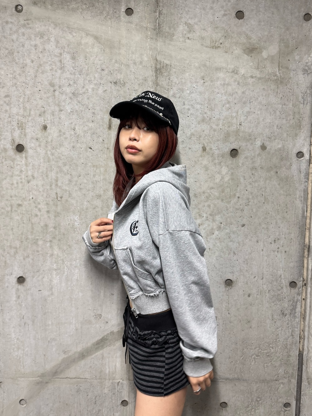 グレー系のパーカー、ブラック系のブーツ、ブラック系のキャップを着用したレディースの秋コーディネートの4枚目の写真