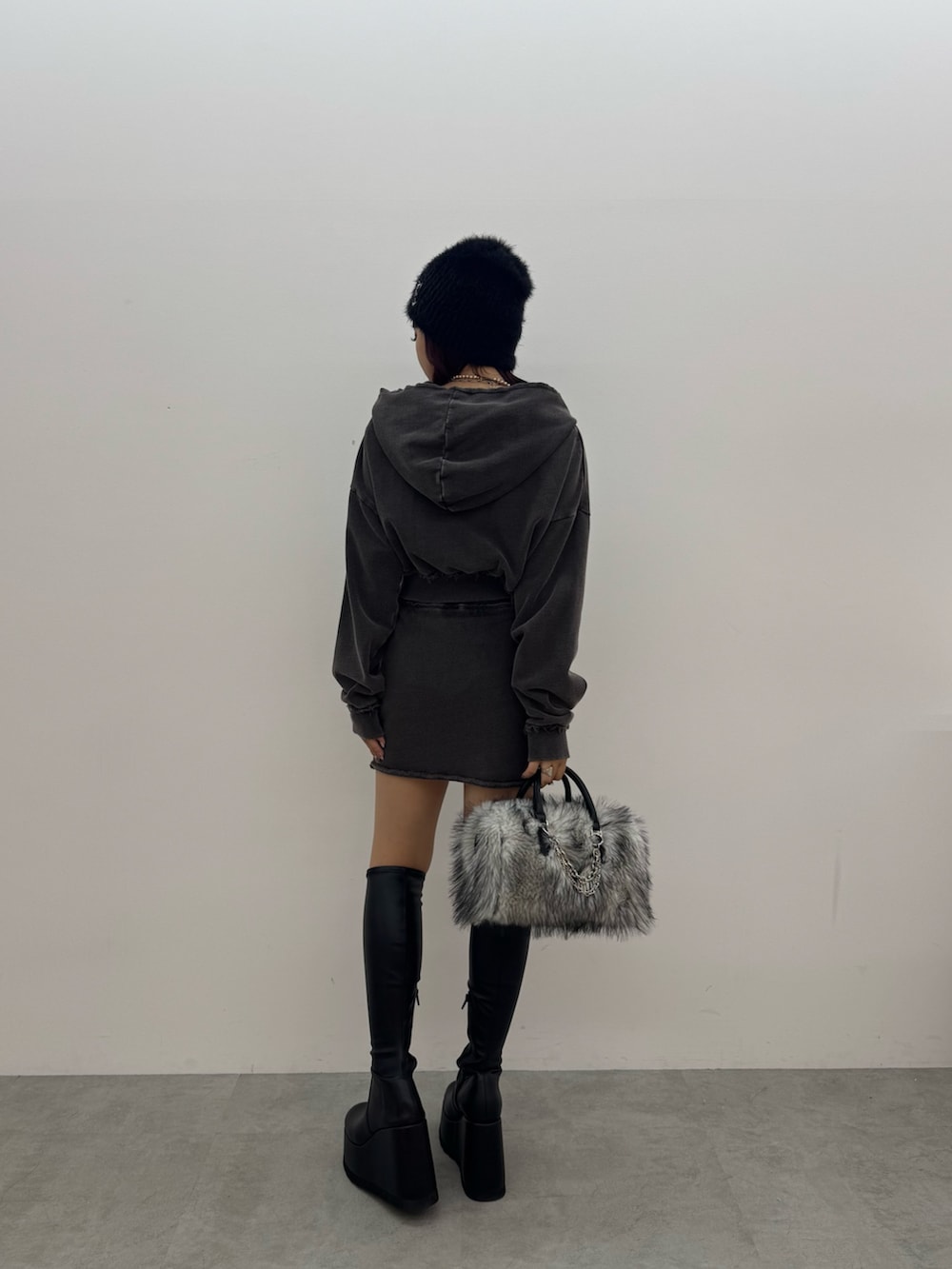 ブラック系のパーカー、ブラック系のスカート、ブラック系のボストンバッグを着用したレディースの秋コーディネートの3枚目の写真