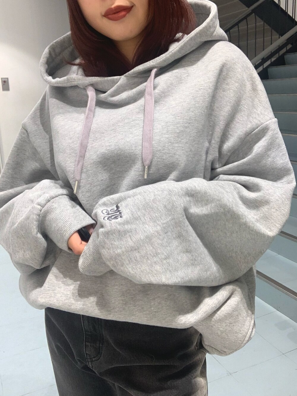 グレー系のパーカー、ブラック系のデニムパンツ、ブラック系のスリッポンを着用したレディースの秋コーディネートの3枚目の写真