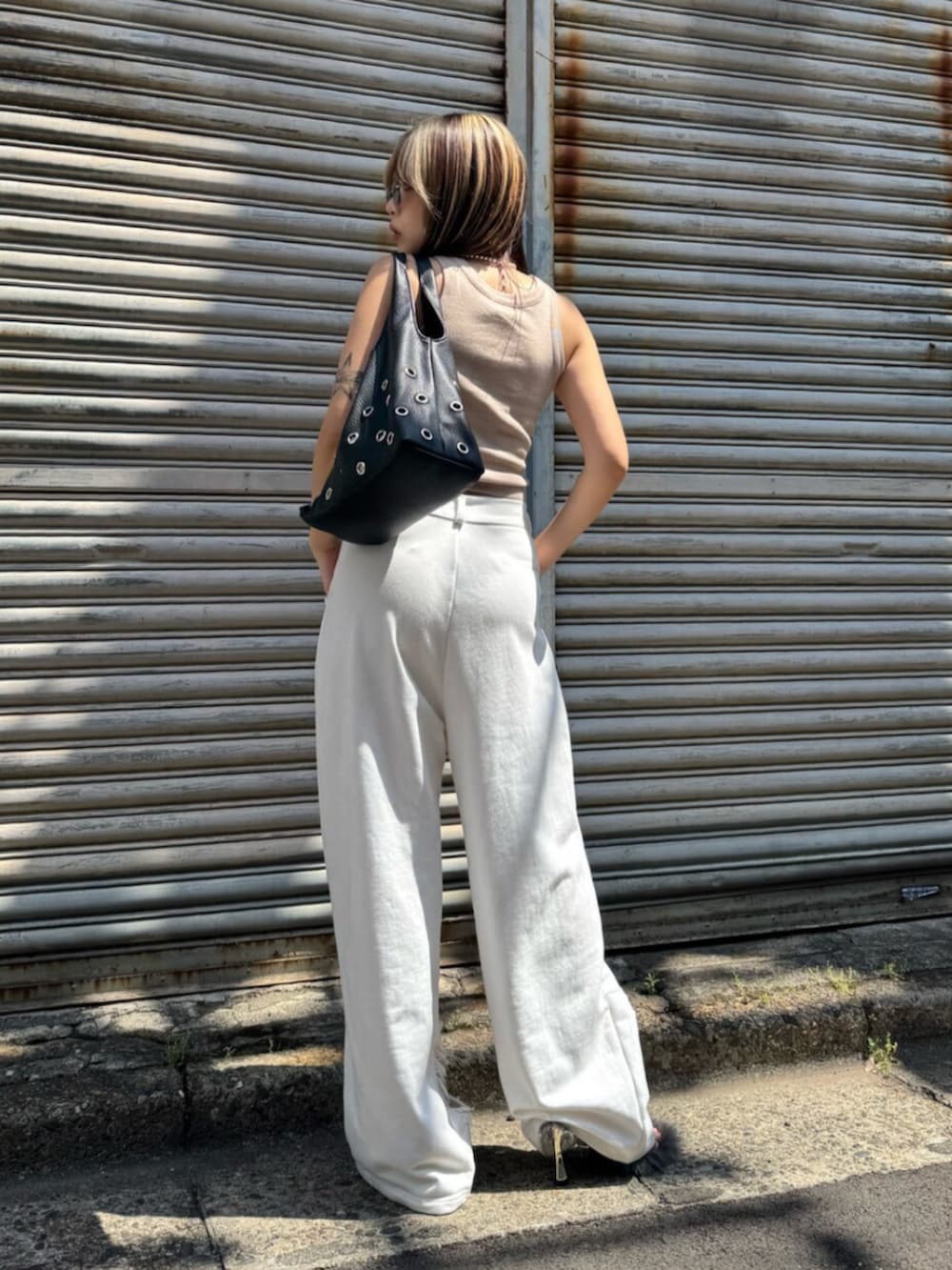 ベージュ系のタンクトップ、ホワイト系のスウェットパンツ、ブラック系のサンダルを着用したレディースの夏コーディネートの3枚目の写真