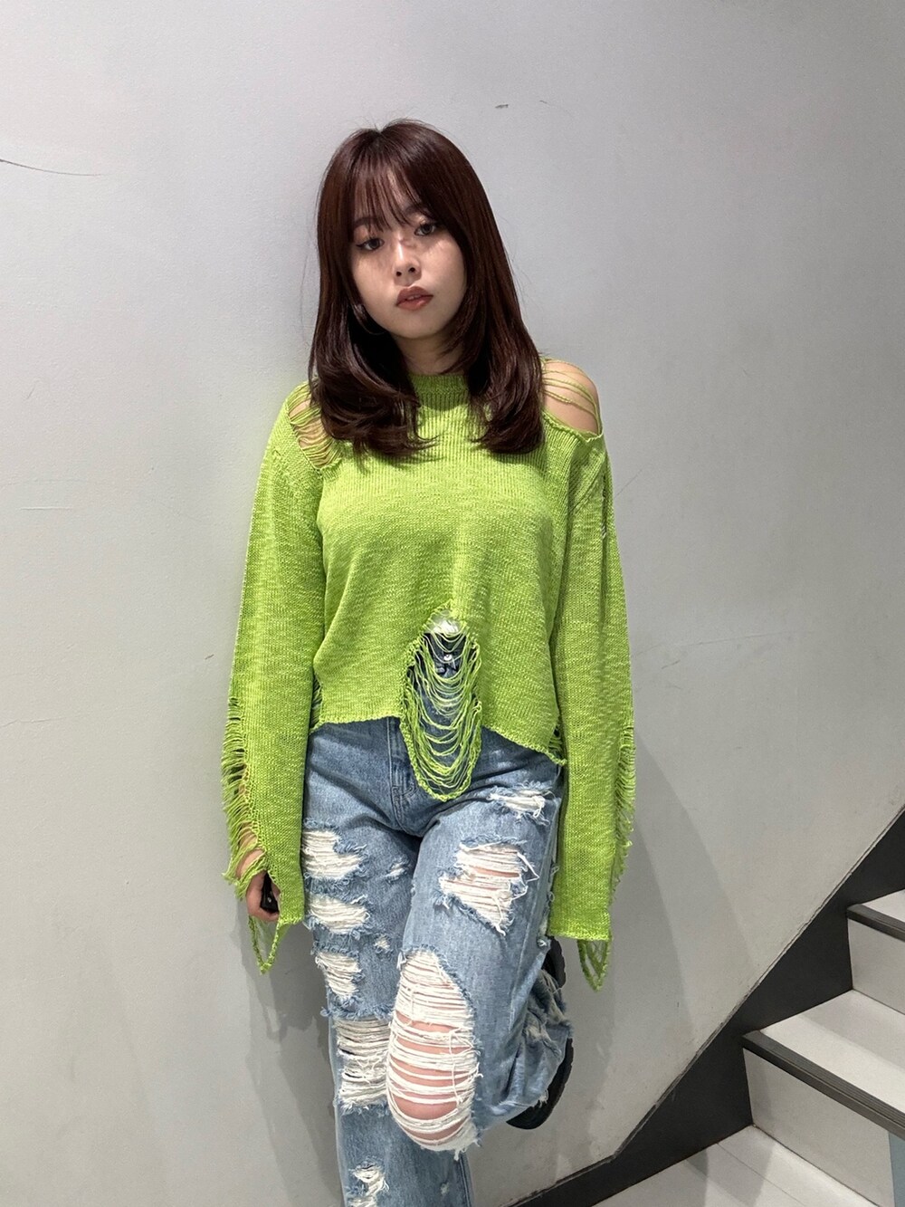 グリーン系のニット/セーター、ブルー系のデニムパンツ、ブラック系のブーツを着用したレディースの春コーディネートの3枚目の写真