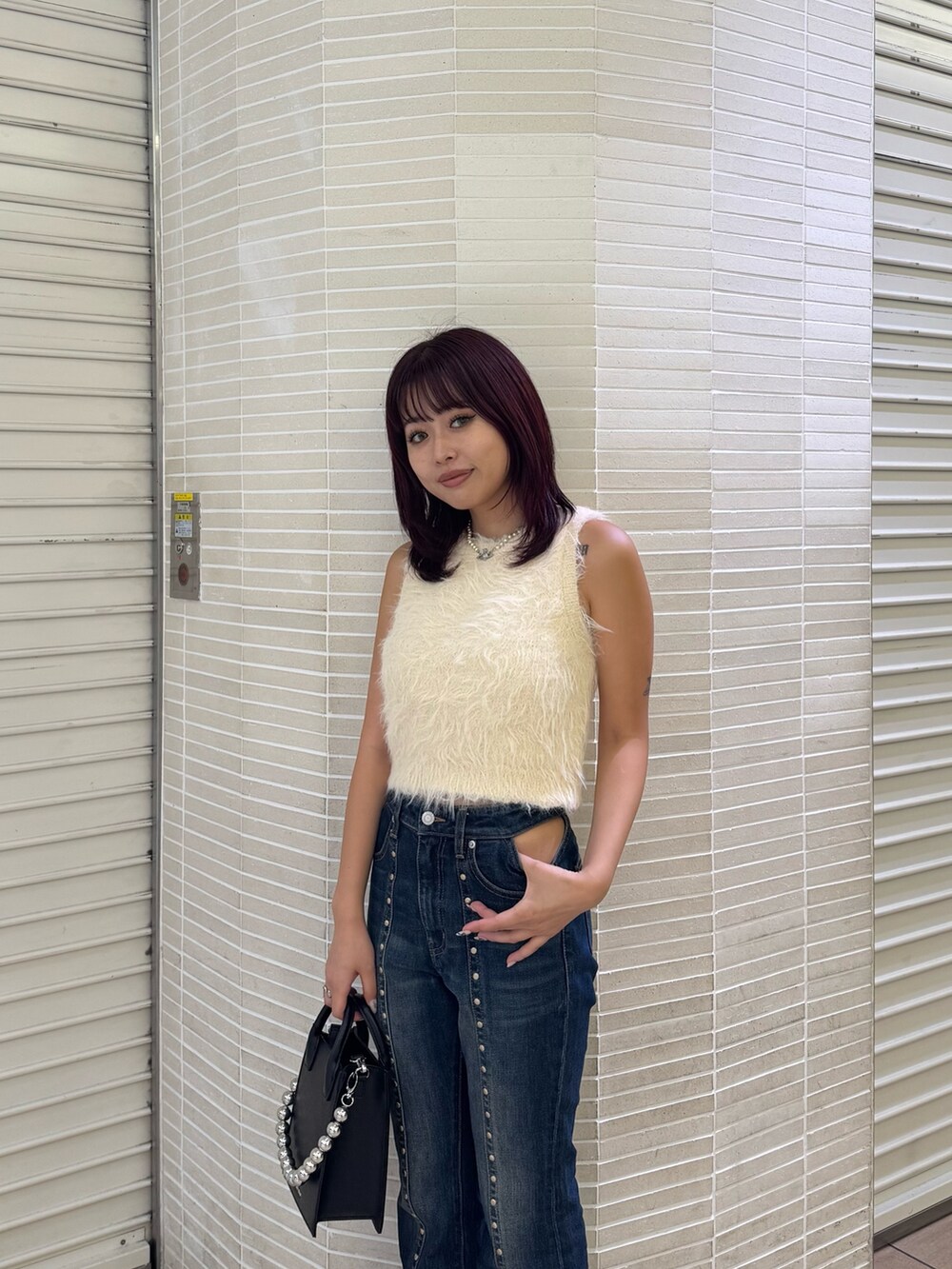 ホワイト系のタンクトップ、ブルー系のデニムパンツ、ブラック系のショルダーバッグを着用したレディースの夏コーディネートの4枚目の写真