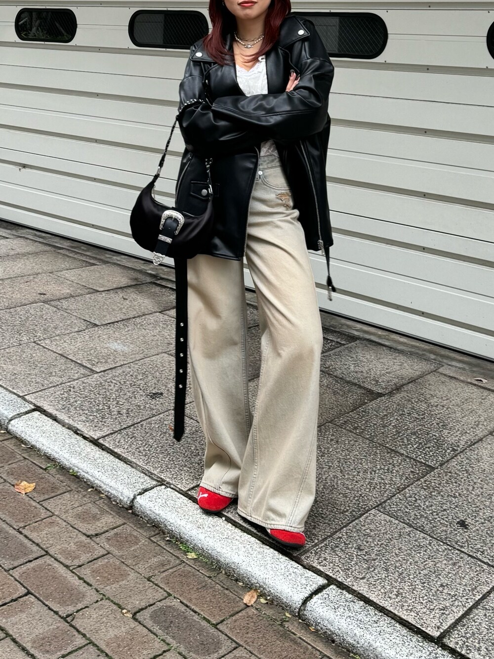 ホワイト系のキャミソール、ブラック系のライダースジャケット、ベージュ系のデニムパンツを着用したレディースの冬コーディネートの3枚目の写真