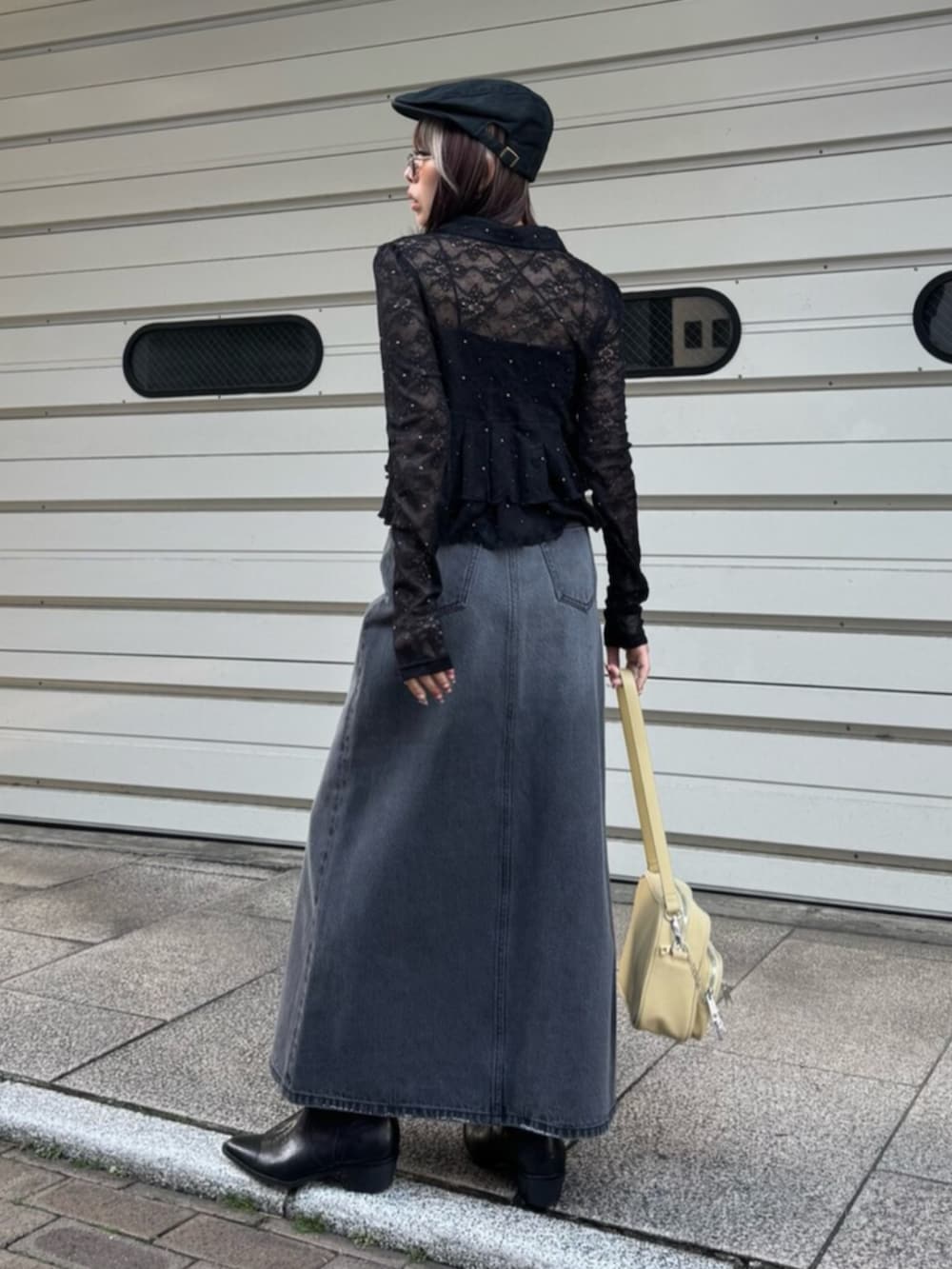 イエロー系のハンドバッグ、ブラック系のシャツ/ブラウス、ブラック系のデニムスカートを着用したレディースの春コーディネートの3枚目の写真