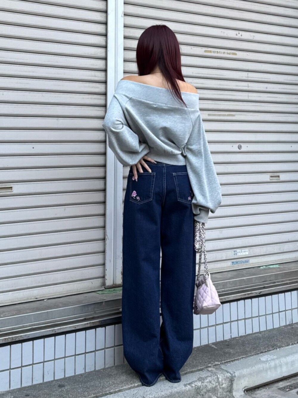 シルバー系のパンプス、グレー系のスウェット、ピンク系のショルダーバッグを着用したレディースの冬コーディネートの3枚目の写真