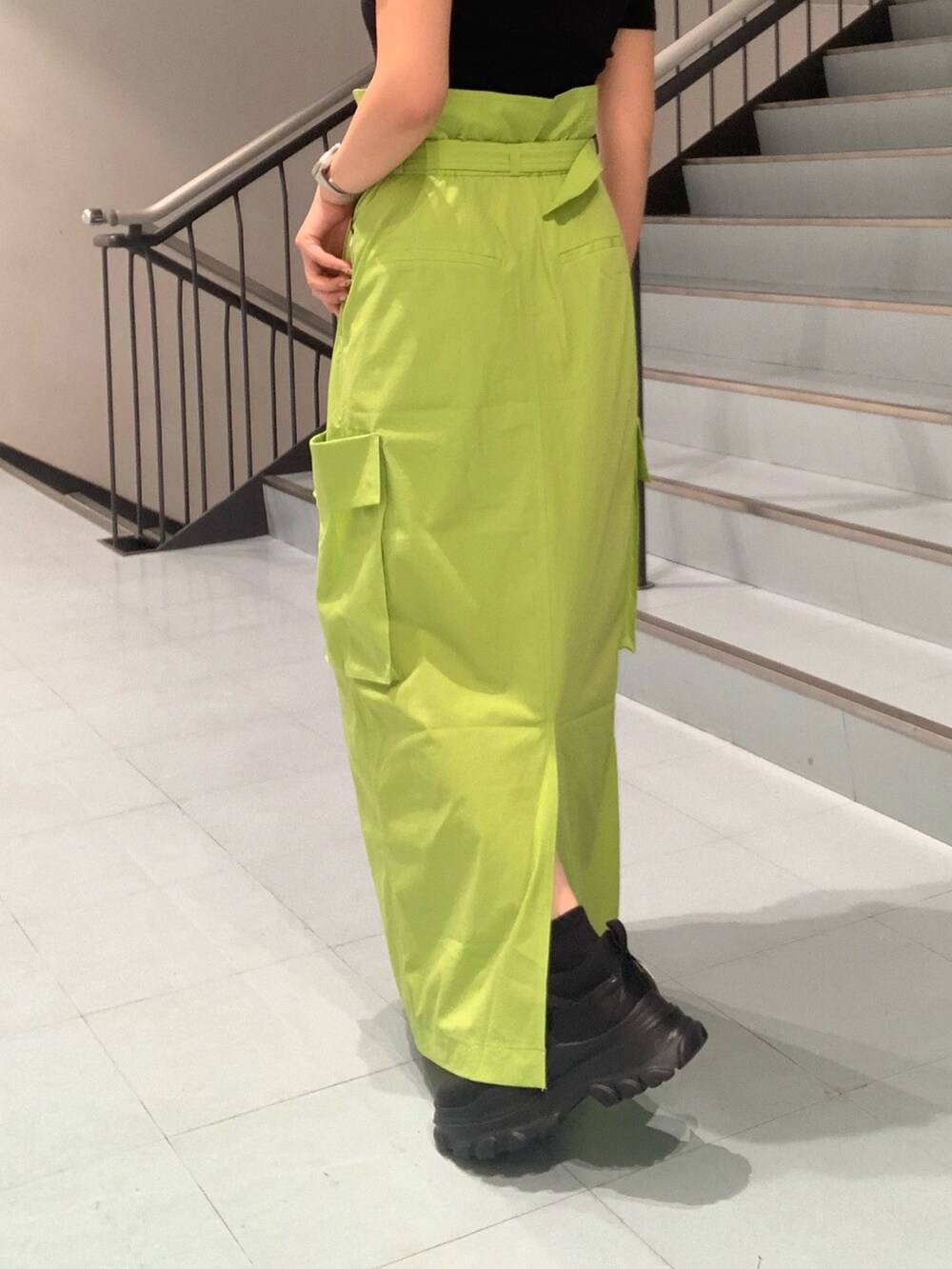 ブラック系のTシャツ/カットソー、グリーン系のスカート、ブラック系のスニーカーを着用したレディースの春コーディネートの6枚目の写真