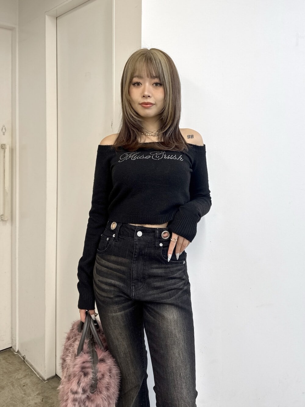 ブラック系のニット/セーター、ブラック系のデニムパンツ、ピンク系のボストンバッグを着用したレディースの夏コーディネートの4枚目の写真