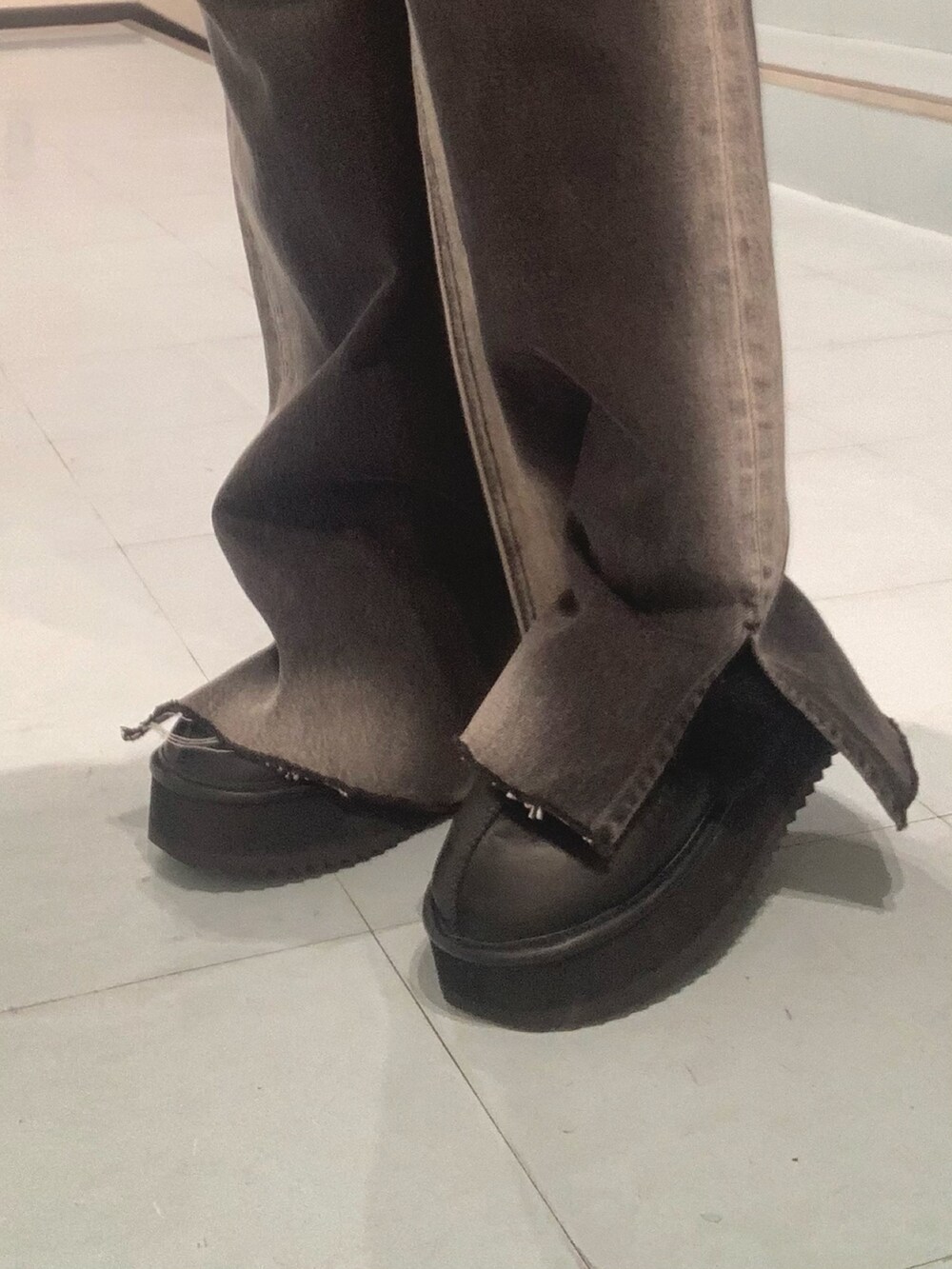 グレー系のパーカー、ブラック系のデニムパンツ、ブラック系のスリッポンを着用したレディースの秋コーディネートの6枚目の写真