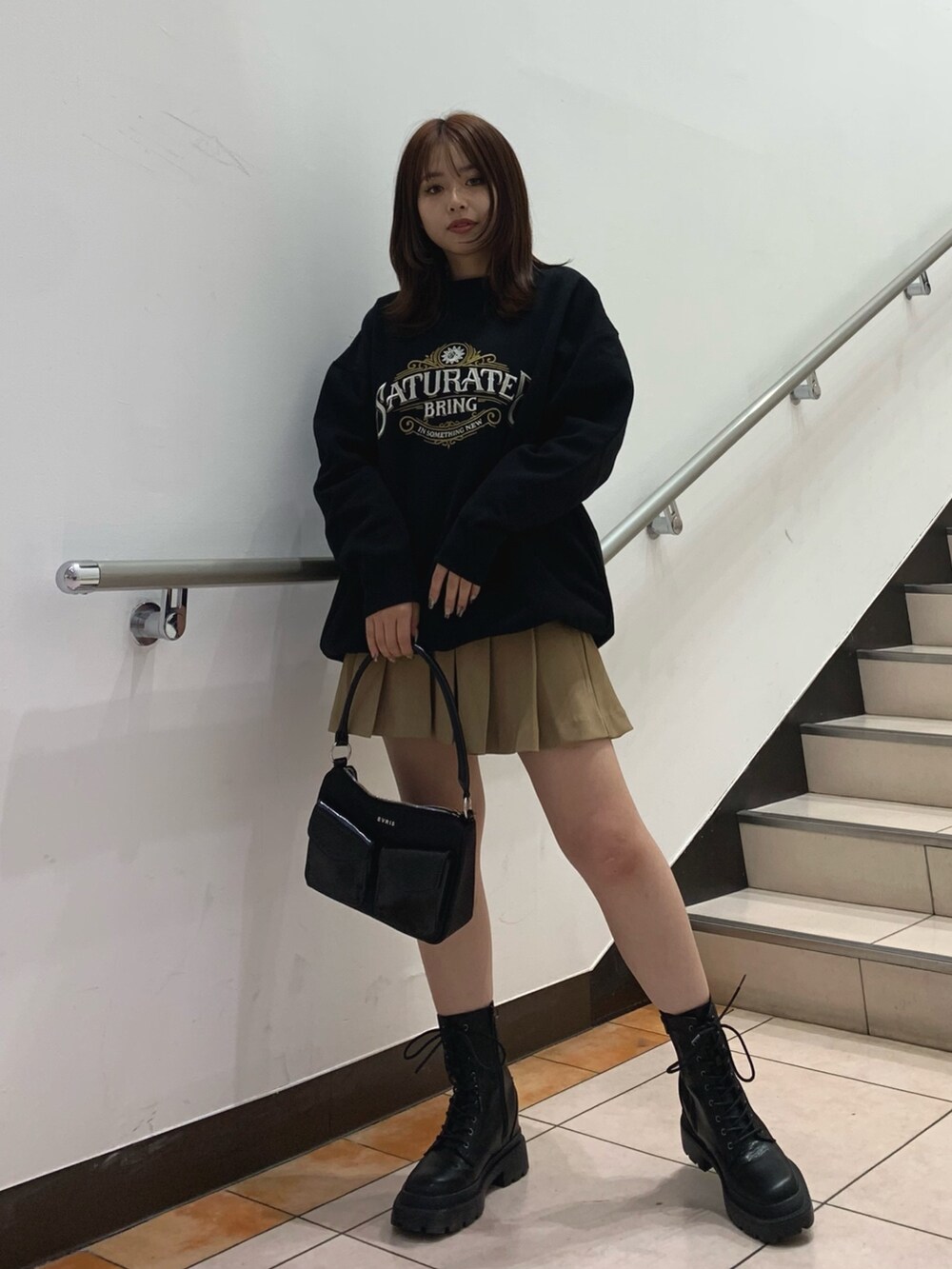 ブラック系のスウェット、ベージュ系のスカート、ブラック系のハンドバッグを着用したレディースの秋コーディネートの2枚目の写真