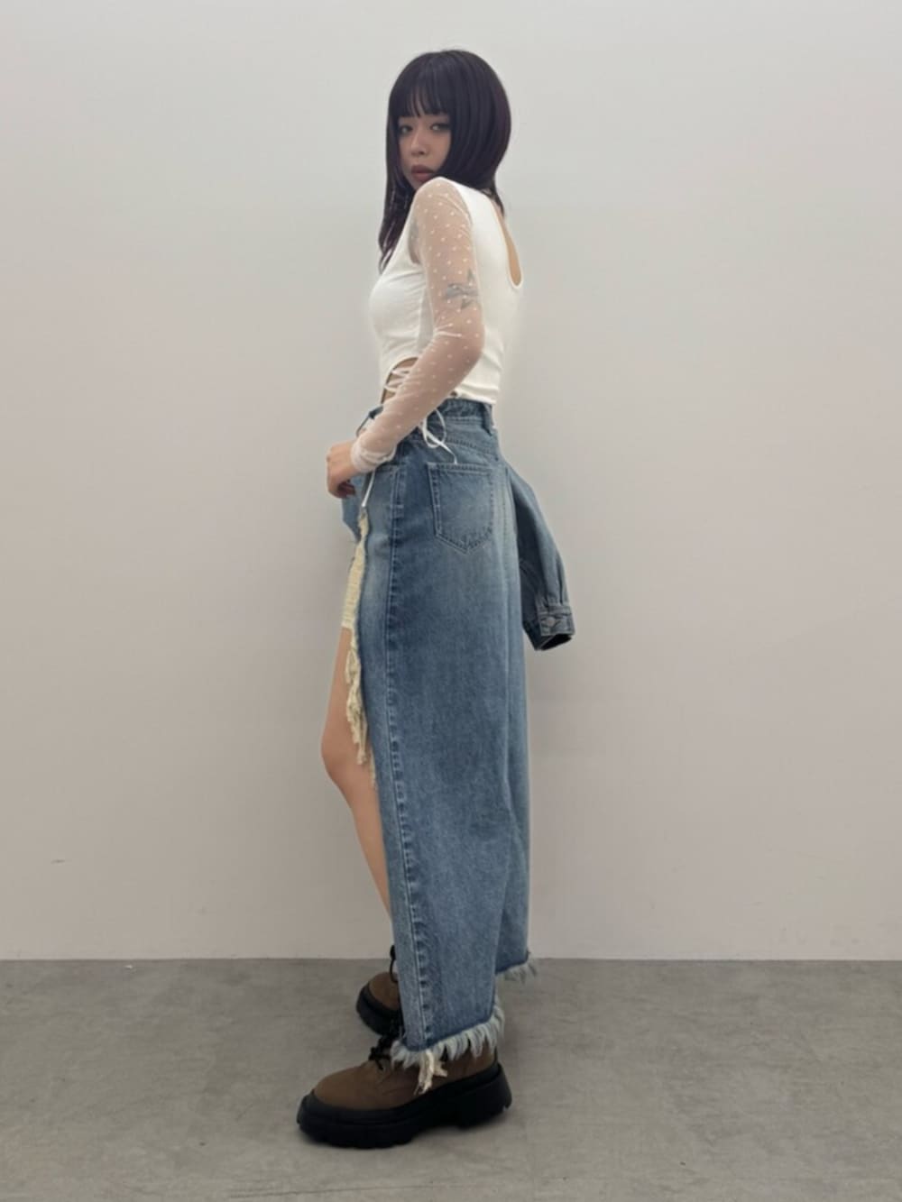 ブラウン系のショルダーバッグ、ホワイト系のTシャツ/カットソー、ブルー系のデニムスカートを着用したレディースの春コーディネートの2枚目の写真