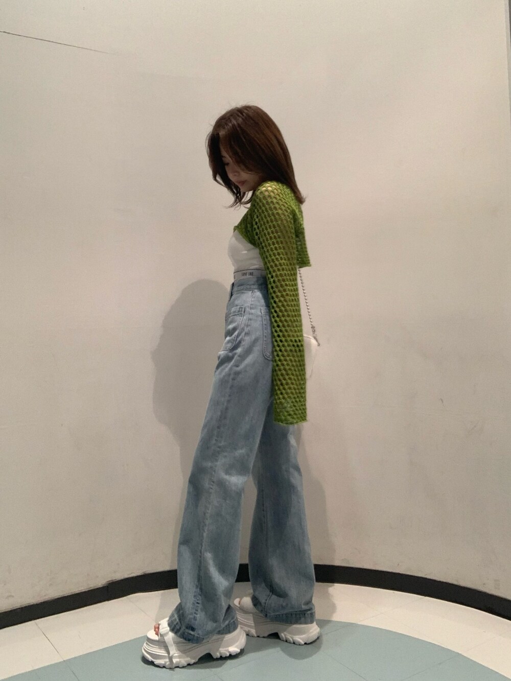 ホワイト系のサンダル、ブルー系のデニムパンツ、ホワイト系のキャミソールを着用したレディースの春コーディネートの2枚目の写真