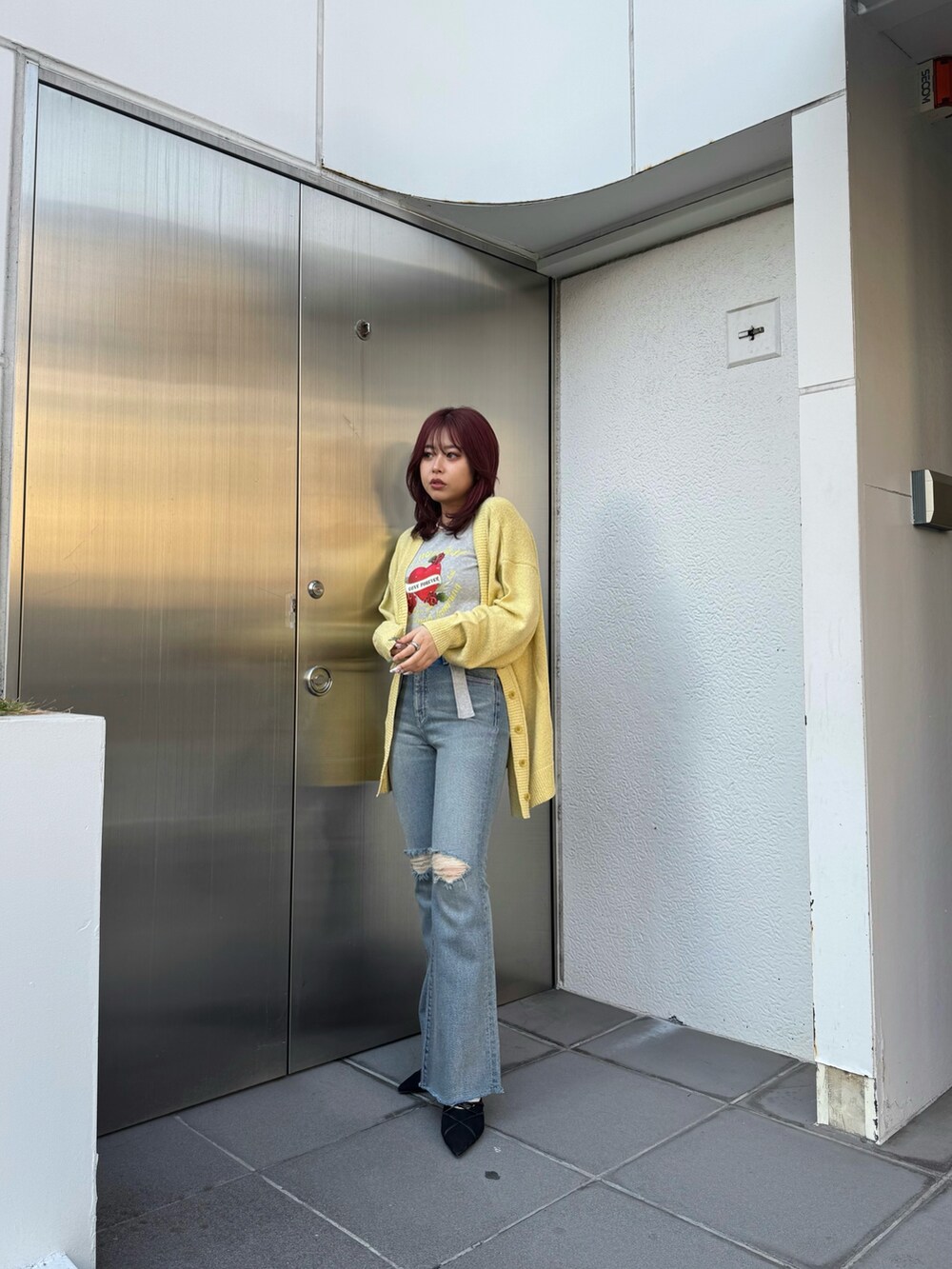 ブラック系のTシャツ/カットソー、イエロー系のカーディガン/ボレロ、ブルー系のデニムパンツを着用したレディースの春コーディネートの2枚目の写真
