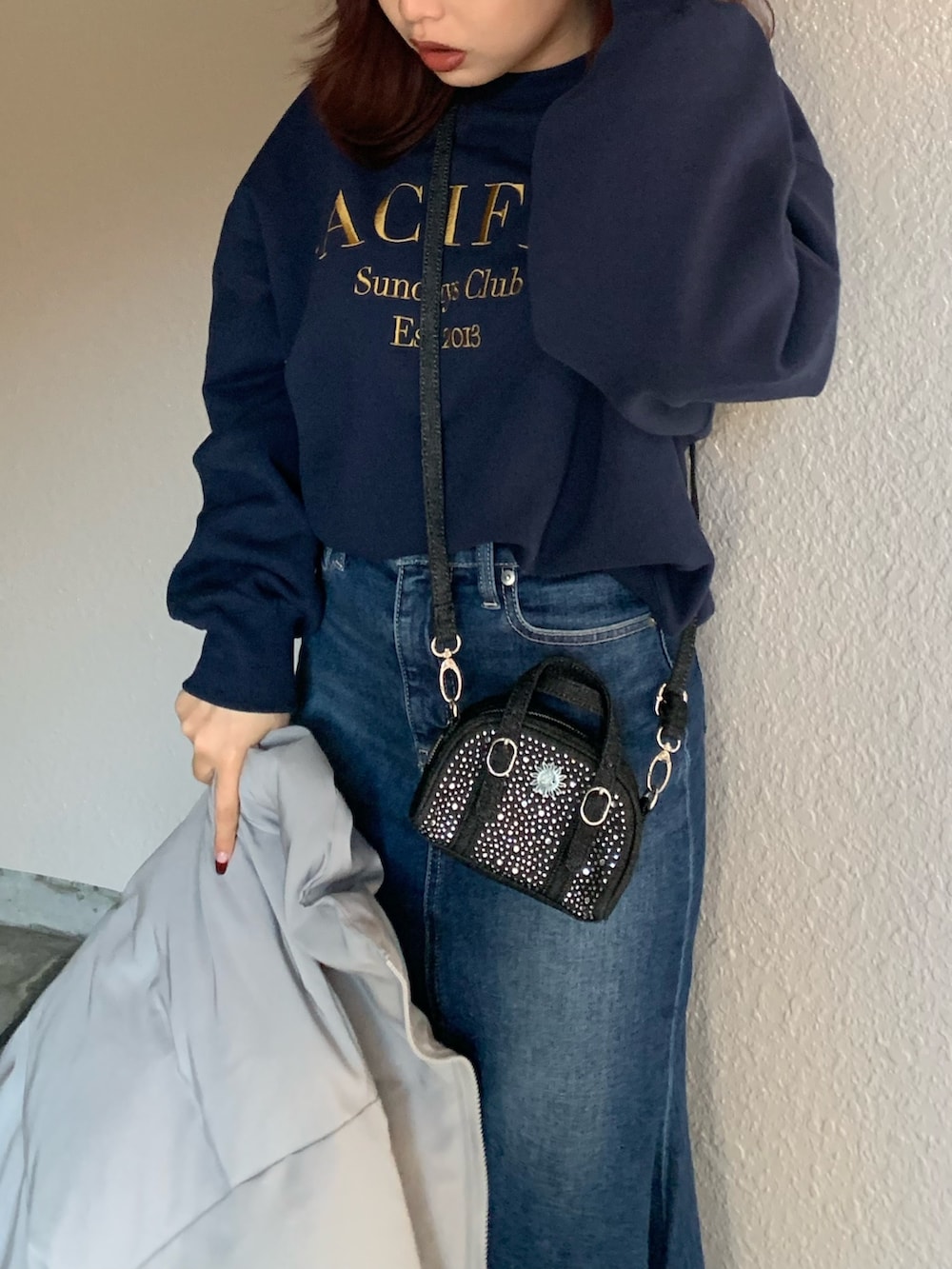 ブラック系のハンドバッグ、ブルー系のスウェット、グレー系のダウンジャケット/コートを着用したレディースの冬コーディネートの3枚目の写真