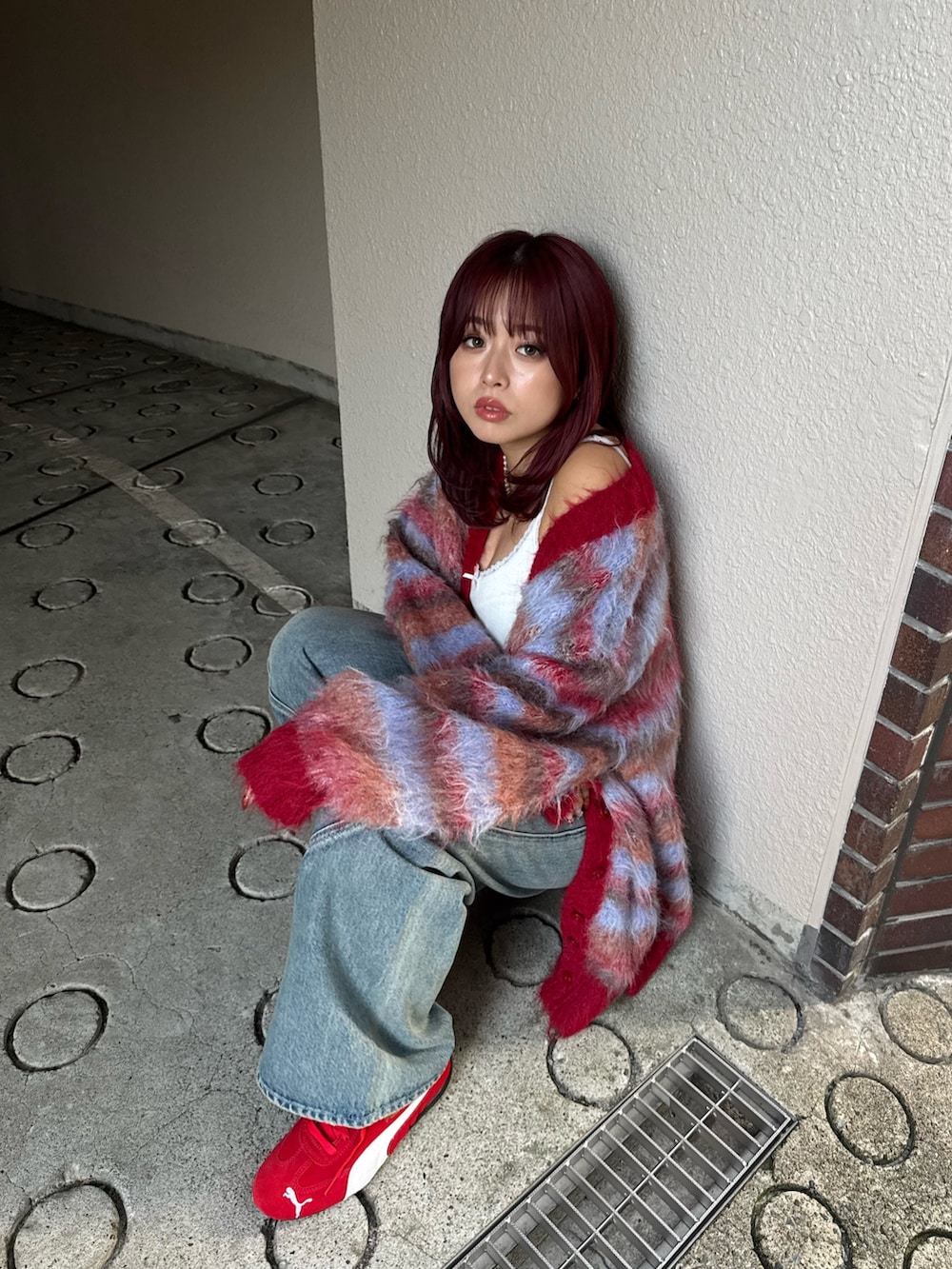 レッド系のカーディガン/ボレロ、ブルー系のデニムパンツ、レッド系のスニーカーを着用したレディースの冬コーディネートの4枚目の写真