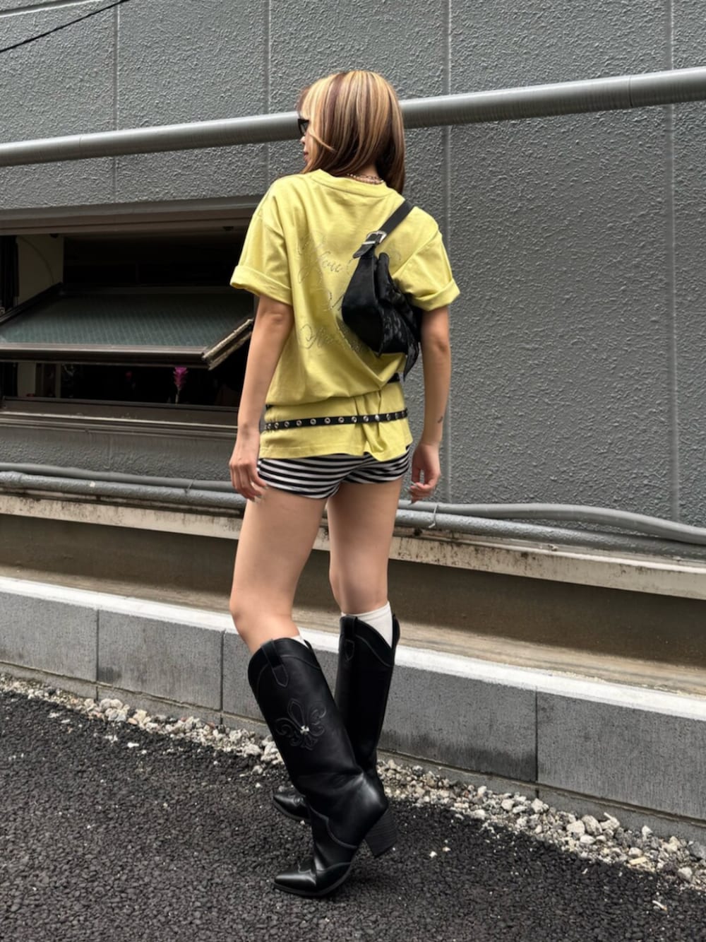 ブラック系のブーツ、ブラック系のハンドバッグ、イエロー系のTシャツ/カットソーを着用したレディースの夏コーディネートの3枚目の写真
