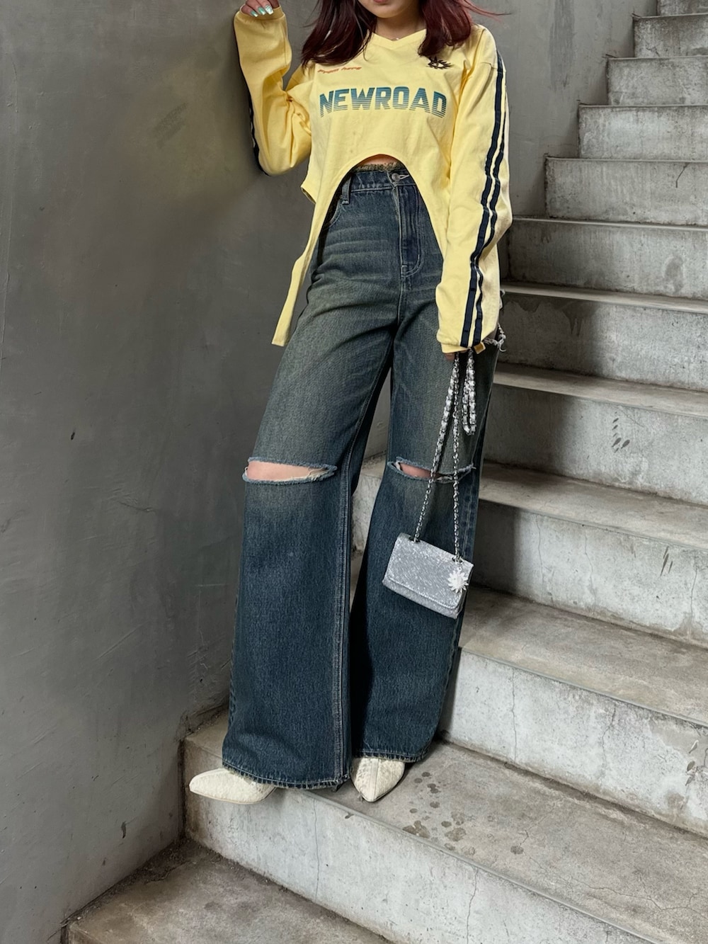 イエロー系のTシャツ/カットソー、ホワイト系のブーツ、シルバー系のショルダーバッグを着用したレディースの冬コーディネートの3枚目の写真