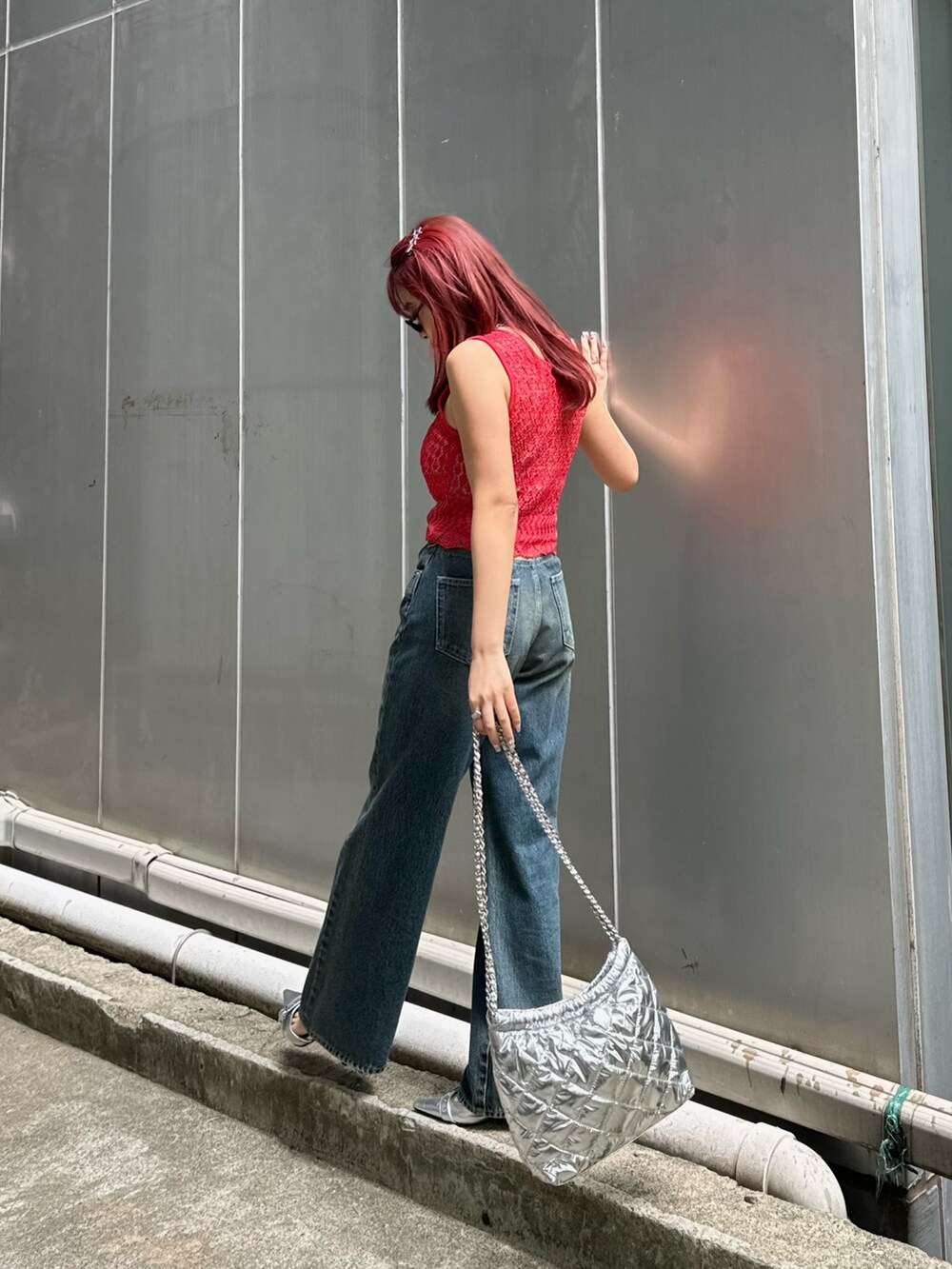 レッド系のニット/セーター、ブルー系のデニムパンツ、シルバー系のショルダーバッグを着用したレディースの春コーディネートの2枚目の写真