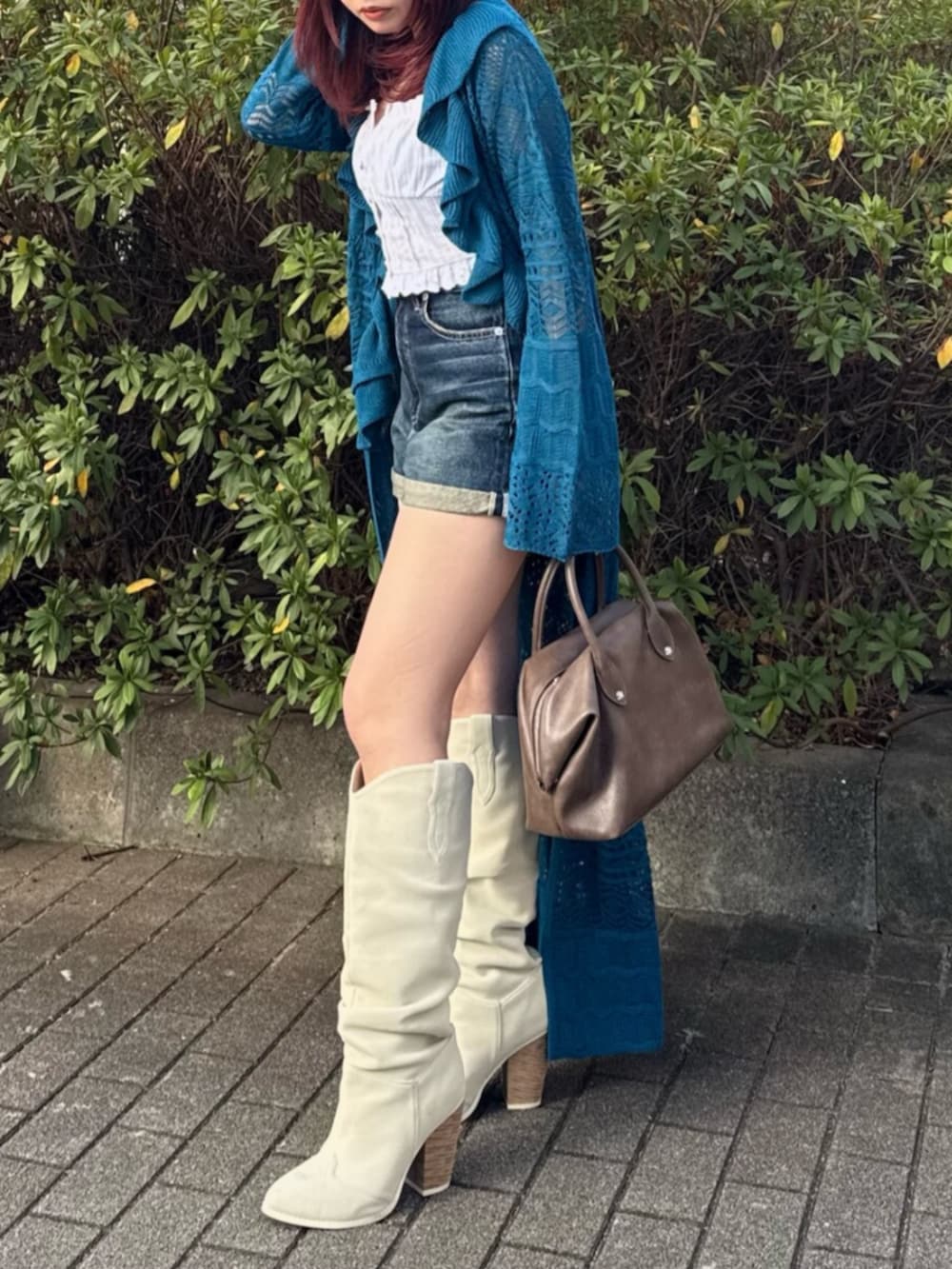 ブラウン系のボストンバッグ、ホワイト系のブーツ、ホワイト系のシャツ/ブラウスを着用したレディースの春コーディネートの2枚目の写真