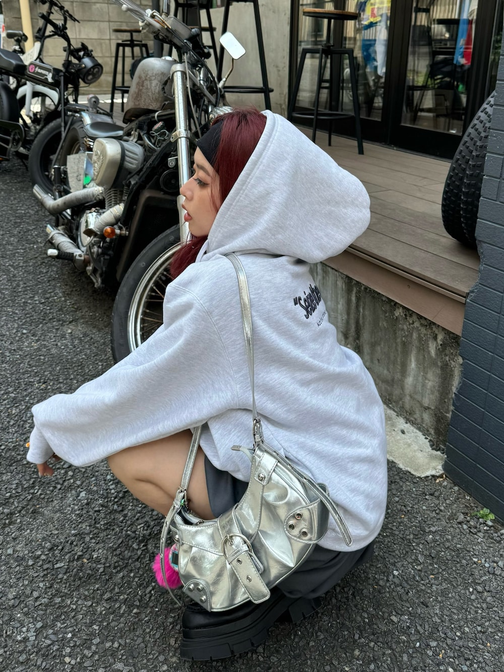 グレー系のパーカー、グレー系のスカート、ブラック系のローファーを着用したレディースの夏コーディネートの4枚目の写真