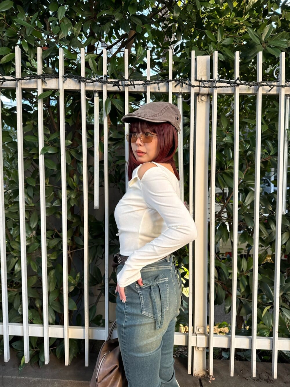 ブラウン系のボストンバッグ、ホワイト系のブーツ、ブルー系のデニムパンツを着用したレディースの春コーディネートの5枚目の写真