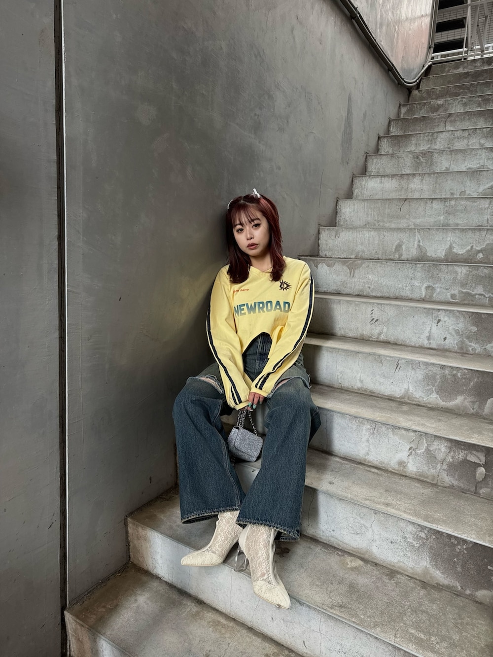 イエロー系のTシャツ/カットソー、ホワイト系のブーツ、シルバー系のショルダーバッグを着用したレディースの冬コーディネートの2枚目の写真