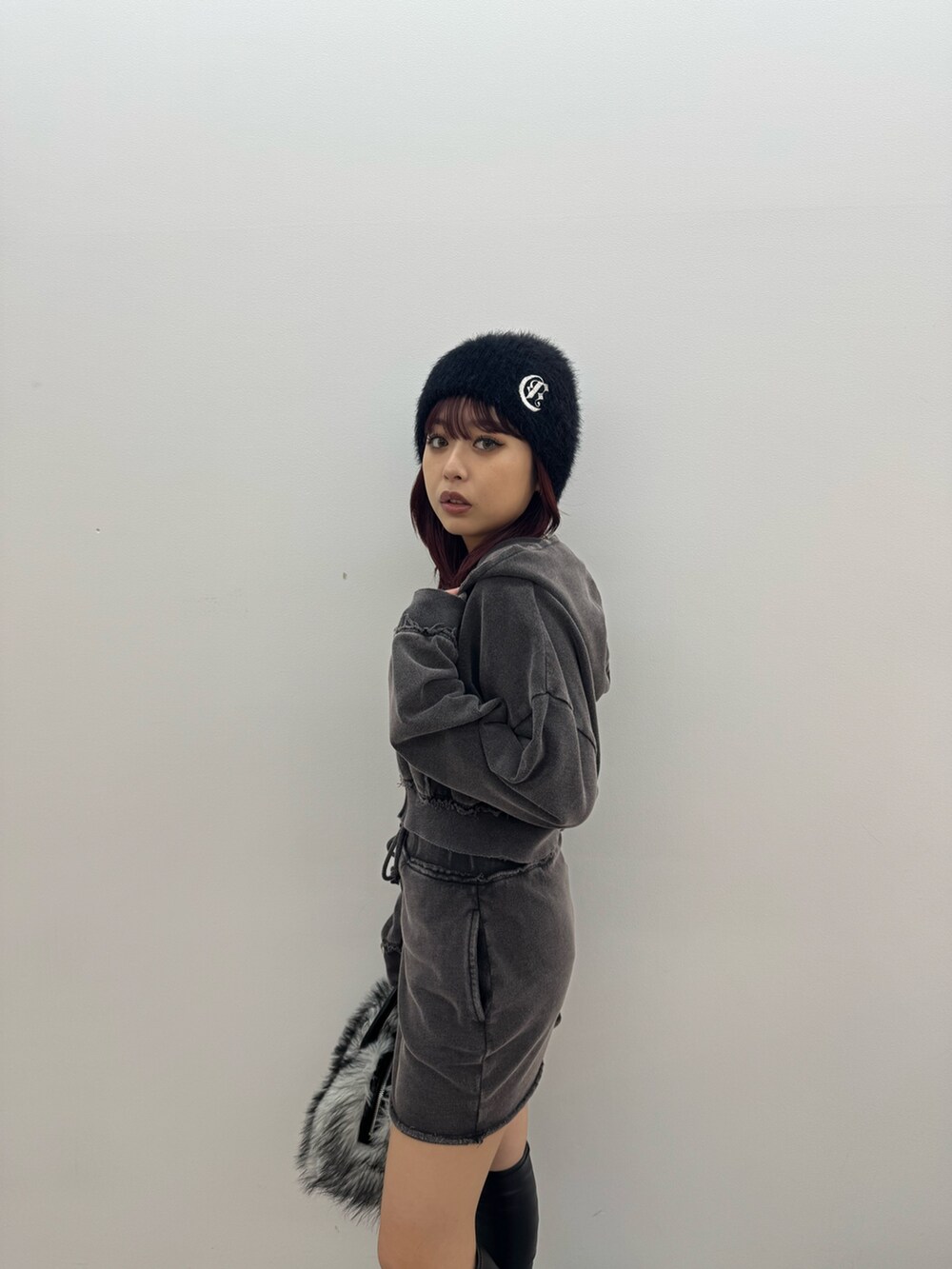 ブラック系のパーカー、ブラック系のスカート、ブラック系のボストンバッグを着用したレディースの秋コーディネートの5枚目の写真