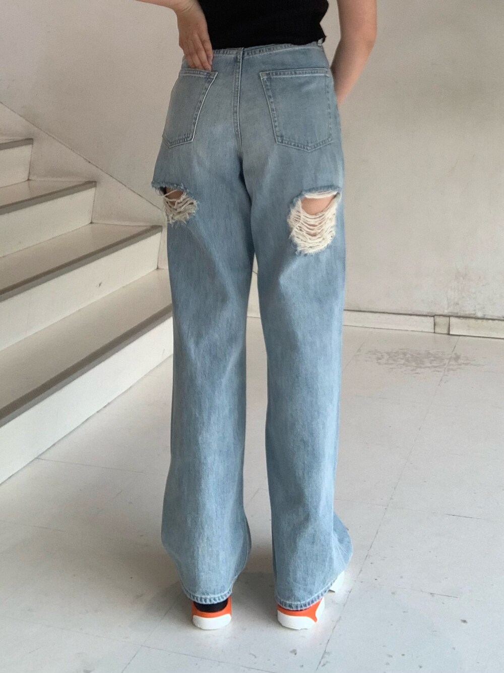 ブラック系のタンクトップ、ブルー系のデニムパンツ、オレンジ系のショルダーバッグを着用したレディースの夏コーディネートの7枚目の写真