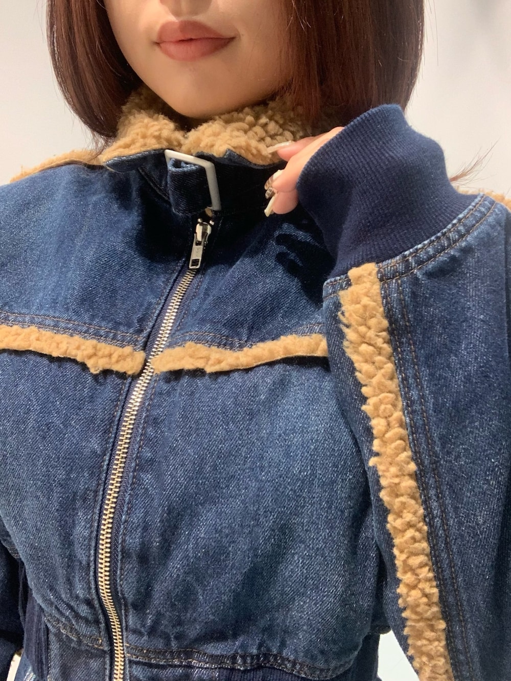 ブルー系のブルゾン、ブルー系のデニムスカート、ブラック系のブーツを着用したレディースの秋コーディネートの4枚目の写真