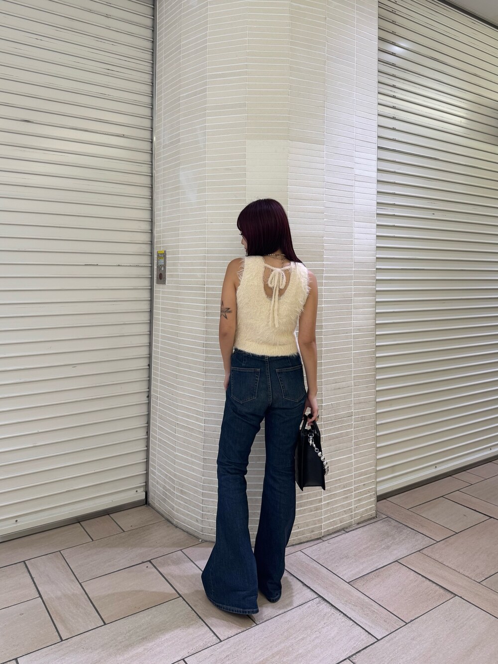 ホワイト系のタンクトップ、ブルー系のデニムパンツ、ブラック系のショルダーバッグを着用したレディースの夏コーディネートの3枚目の写真