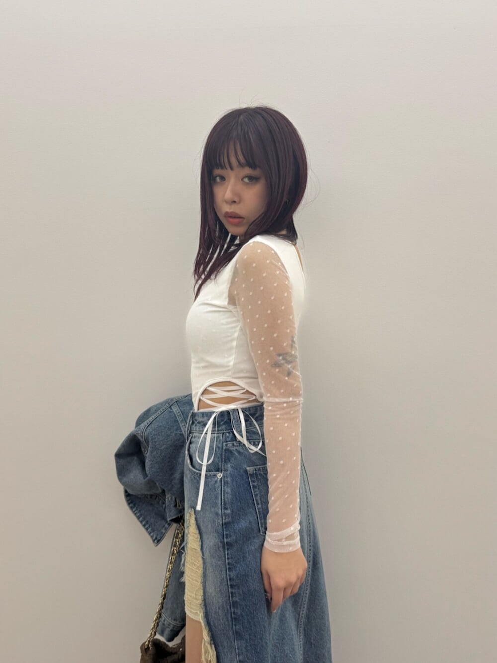 ブラウン系のショルダーバッグ、ホワイト系のTシャツ/カットソー、ブルー系のデニムスカートを着用したレディースの春コーディネートの4枚目の写真