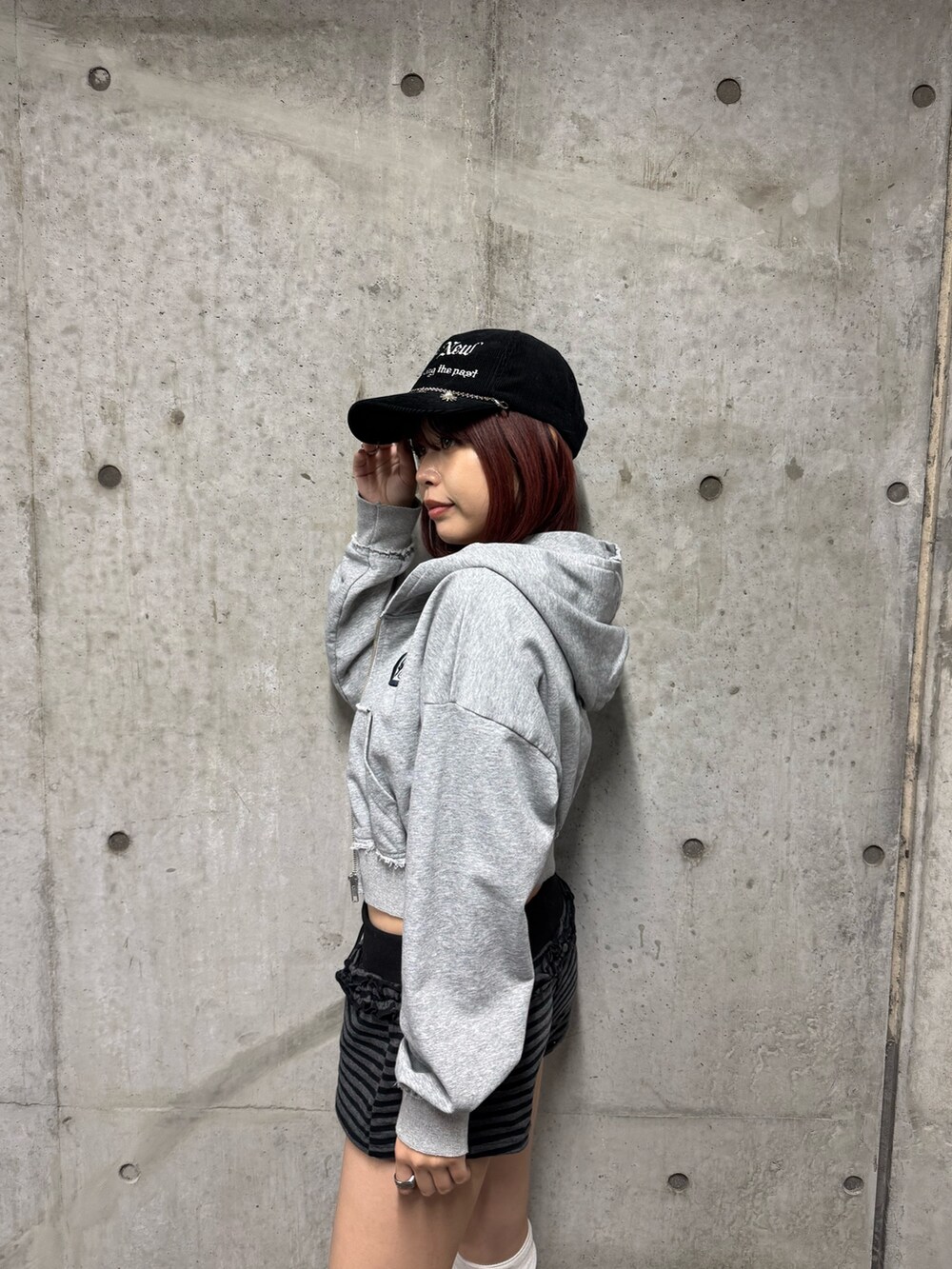 グレー系のパーカー、ブラック系のブーツ、ブラック系のキャップを着用したレディースの秋コーディネートの5枚目の写真