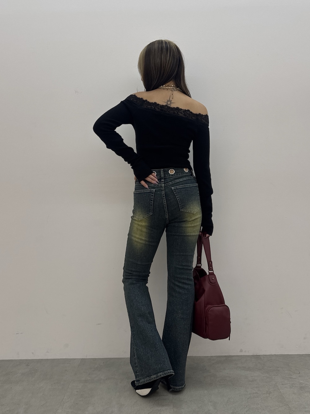 ブラック系のニット/セーター、ブルー系のデニムパンツ、レッド系のハンドバッグを着用したレディースの秋コーディネートの3枚目の写真