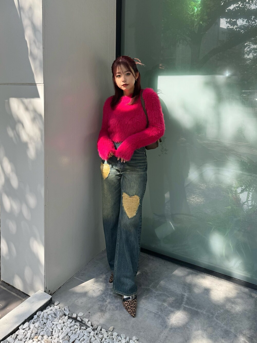 ピンク系のニット/セーター、ブルー系のデニムパンツ、ブラウン系のハンドバッグを着用したレディースの秋コーディネートの2枚目の写真