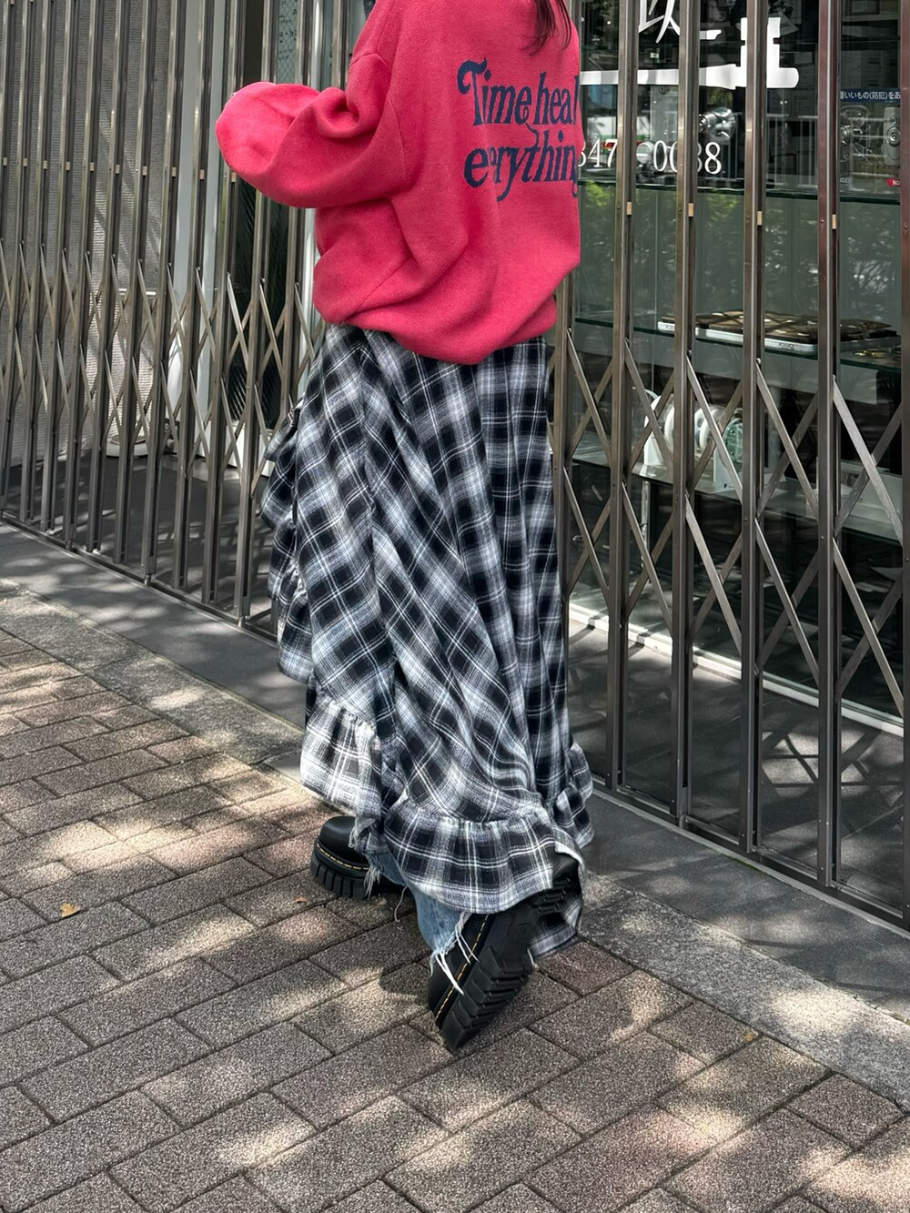 ピンク系のニット/セーター、ブラック系のスカート、ブルー系のデニムパンツを着用したレディースの秋コーディネートの3枚目の写真